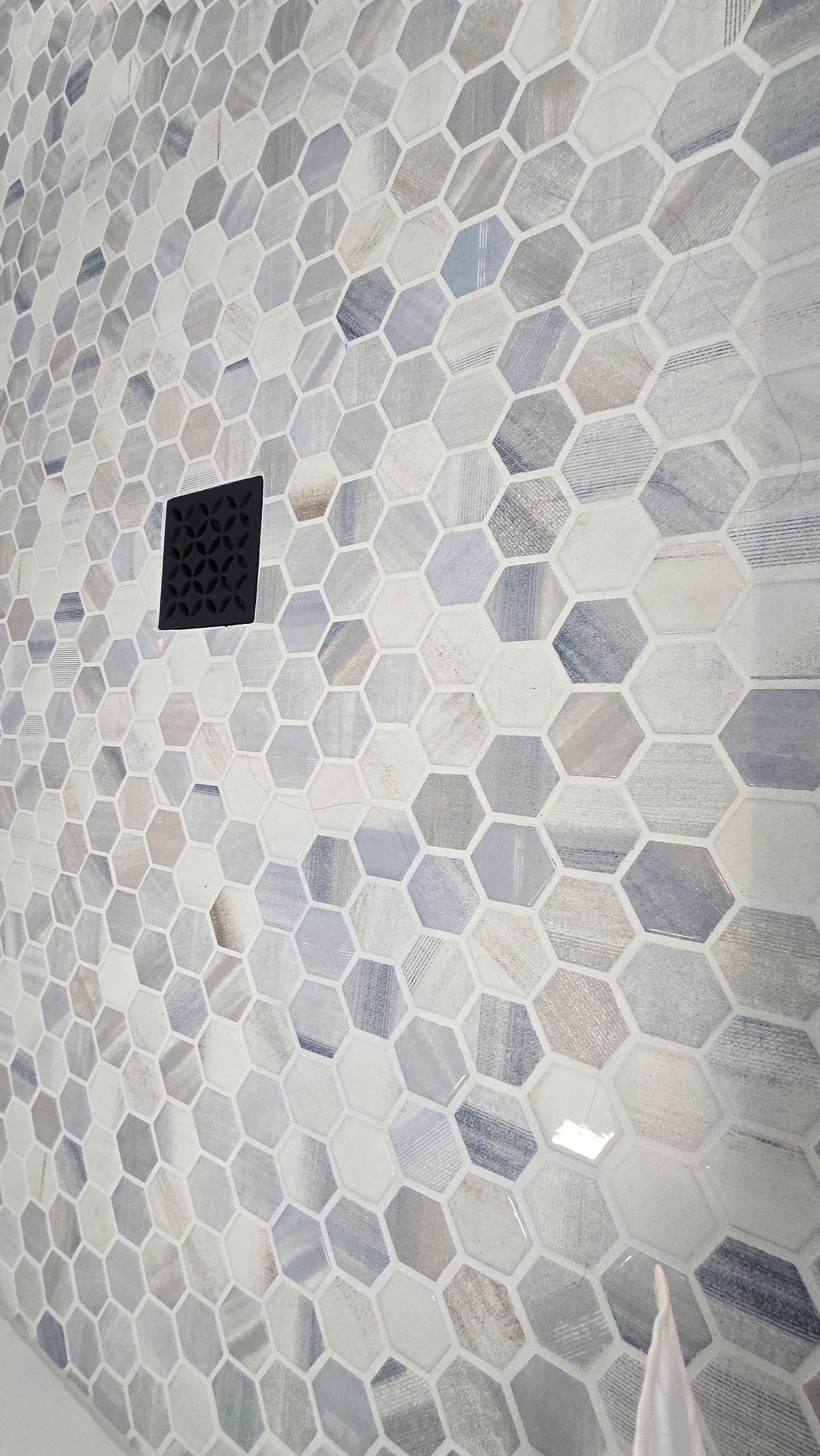 Honeycomb mosaic tile wall with a dark square object.