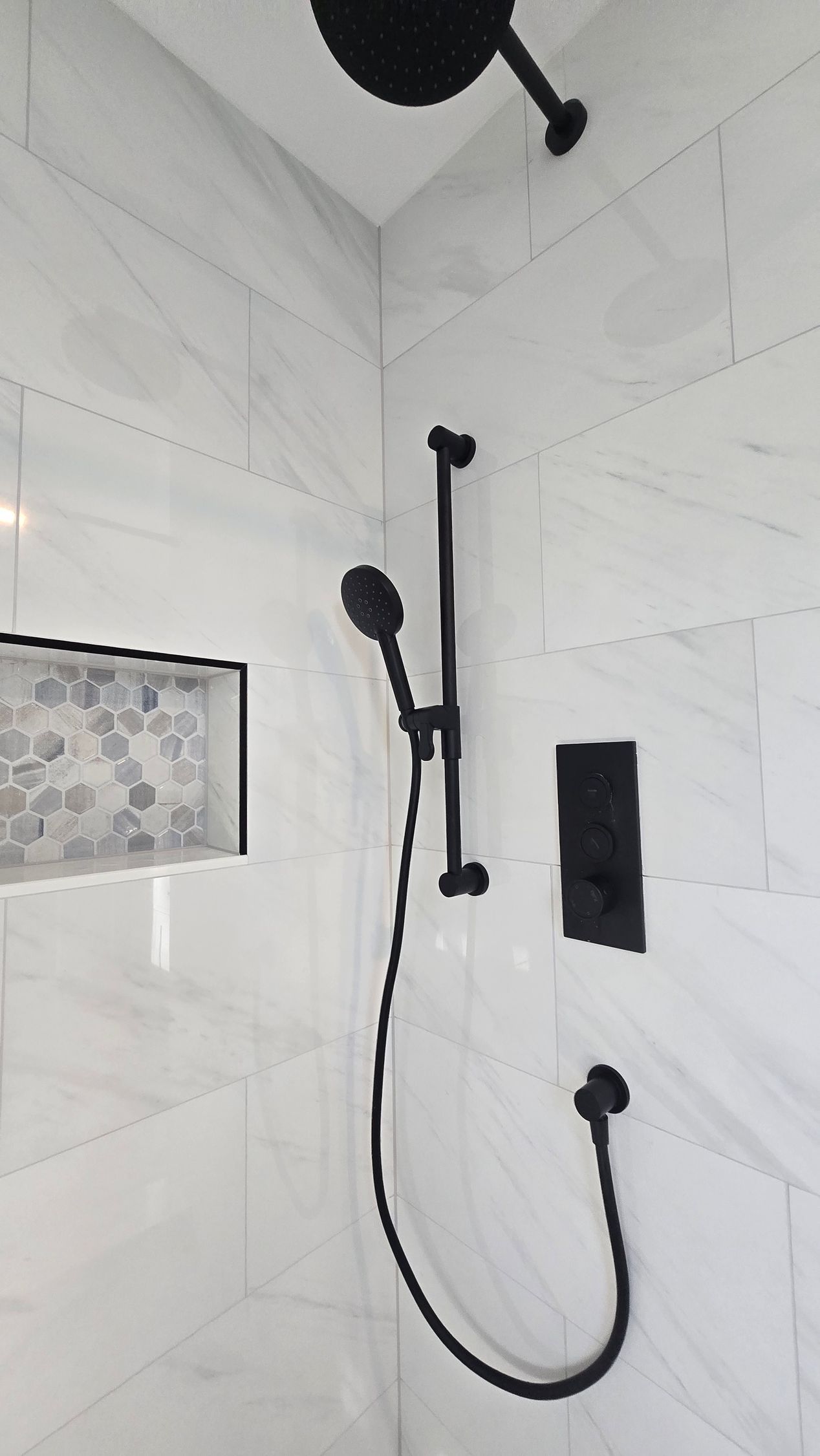 Modern walk-in shower in Wethersfield, CT with white tiled walls and black fixtures.