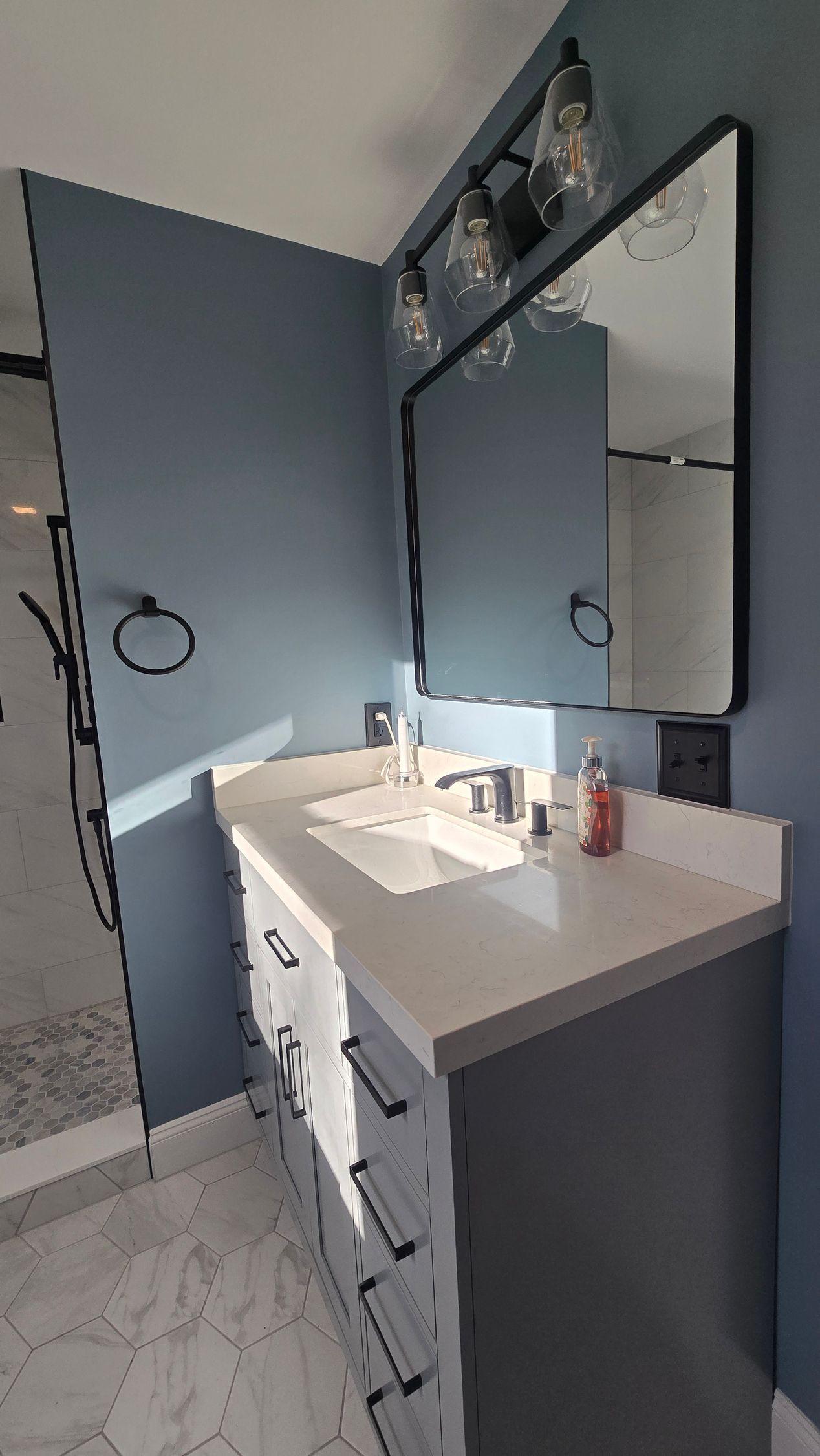 Luxurious walk-in shower renovation in Wolcott, CT with herringbone tile, bronze fixtures, glass enclosure, and a built-in shelf.