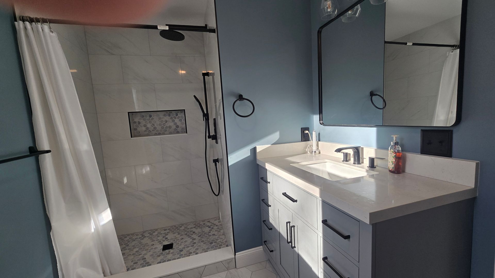 Bristol bathroom with double sinks, large mirror with lightbulbs, and a window.