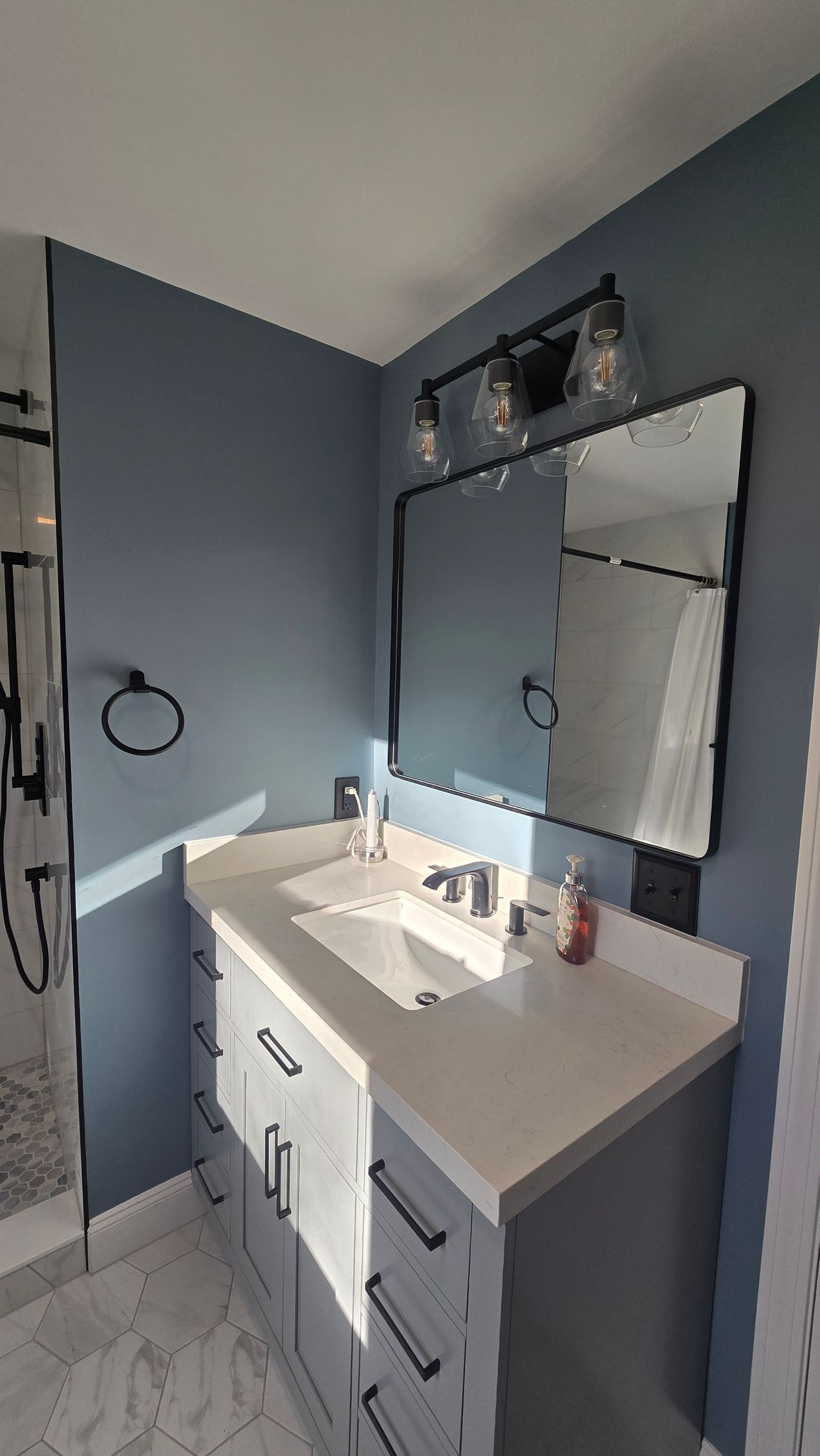 Bristol bathroom with large, illuminated mirror over a white countertop, black faucets, and a sink.