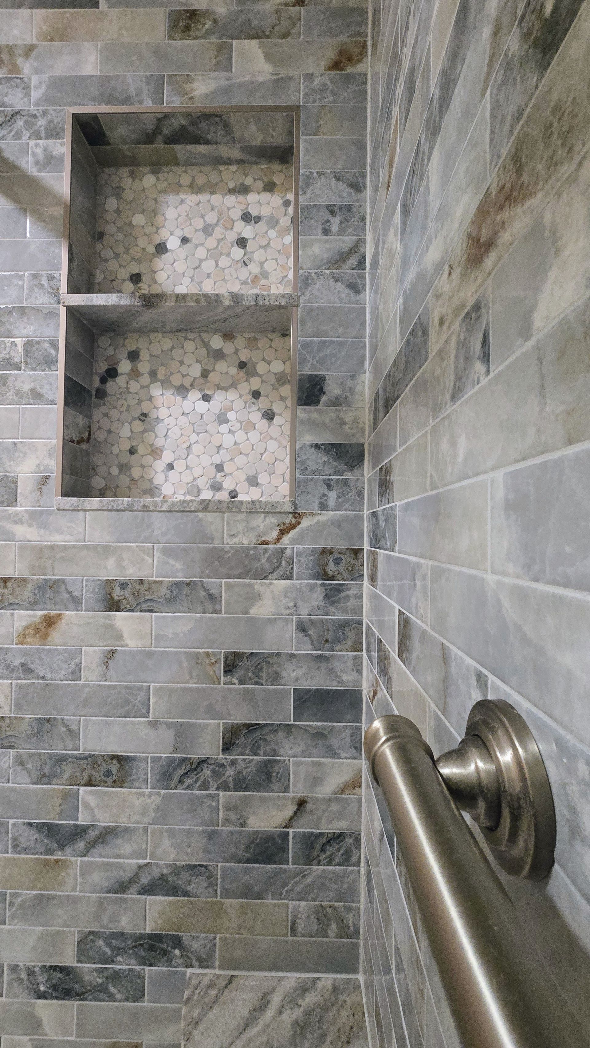 Bristol bathroom with white tub, speckled tile wall, black shower fixtures, and a recessed shelf.