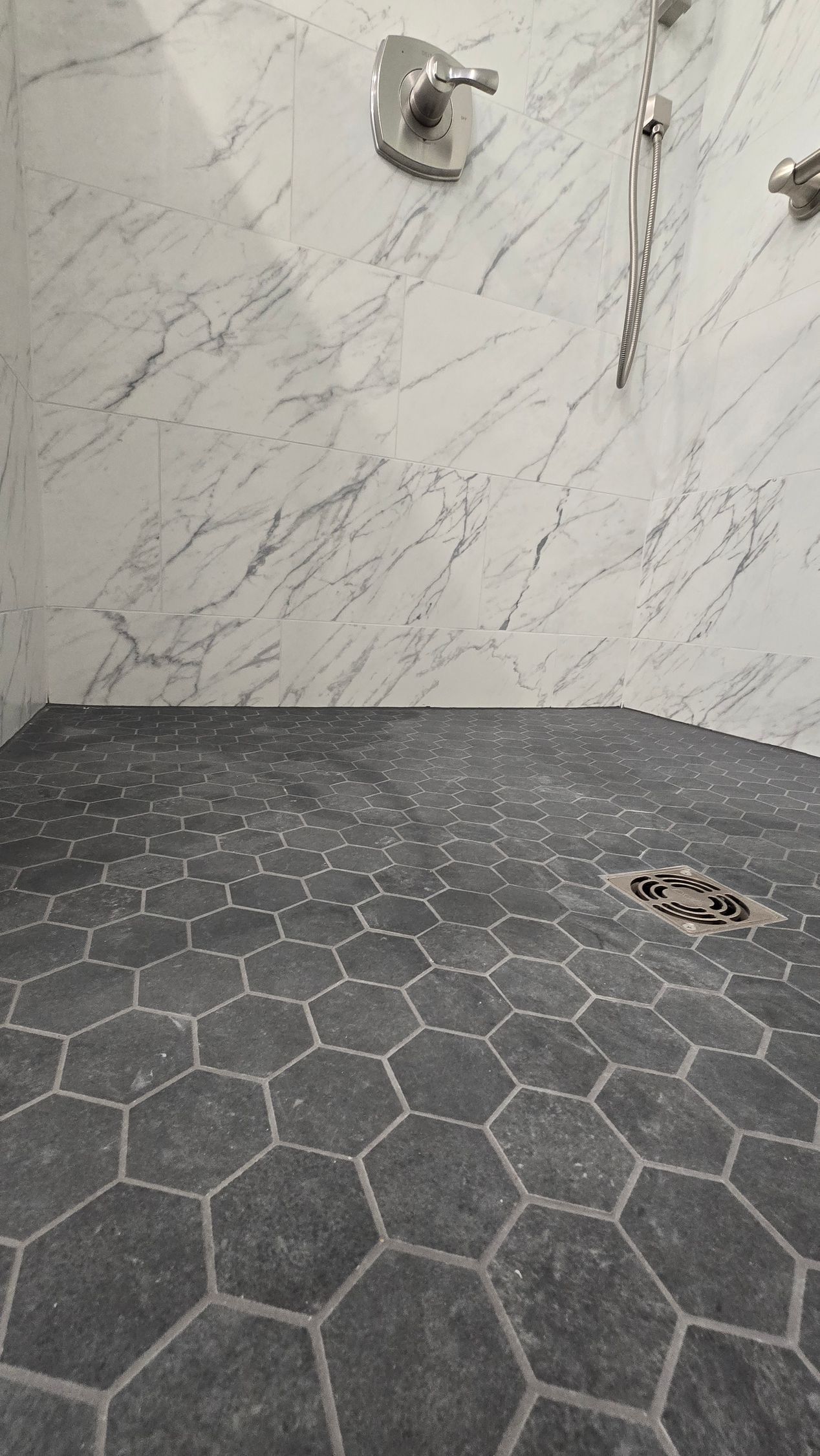 Bathroom with a walk-in shower in Glastonbury, CT with floor with gray hexagon mosaic tiles and marble walls.