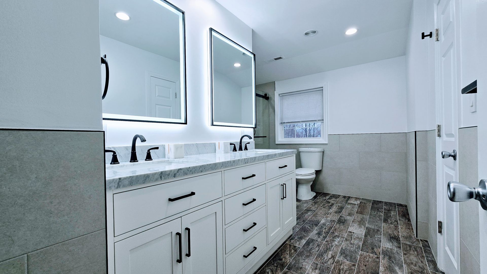 Modern bathroom in Berlin, CTwith white cabinets, dual sinks, black fixtures, and a glass shower.