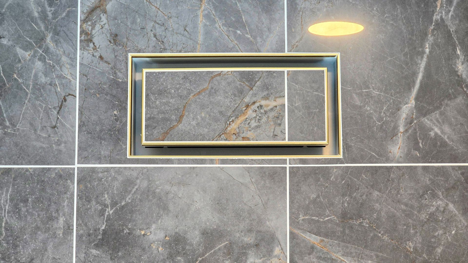 A gold-framed recessed tiled vent cover in Cromwell, CT centered on a grey, marble-patterned tiled floor.