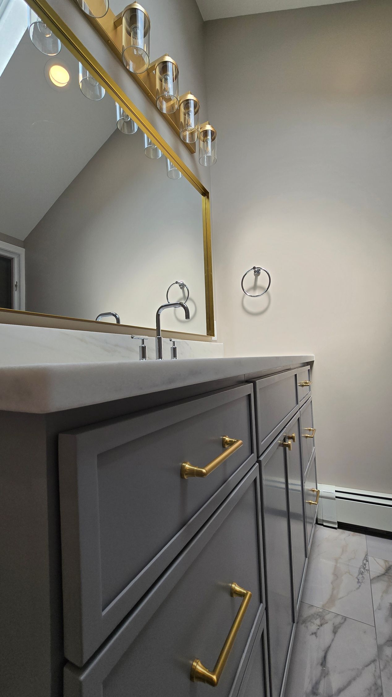 Modern bathroom vanity with gold hardware, mirror, and gray marble-style floor tiles