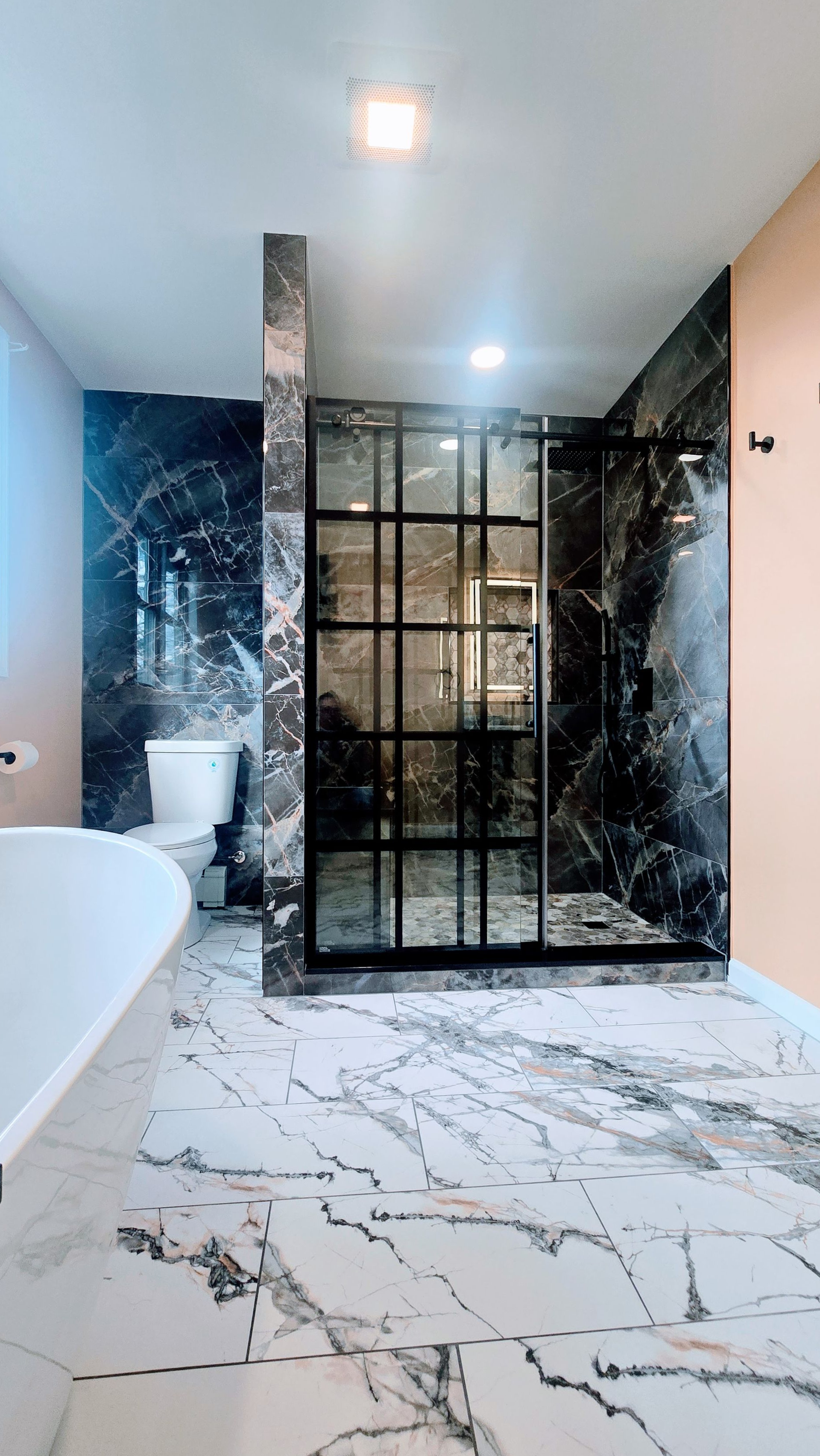 Luxurious bathroom in Seymour, CT completed by First Choice Bathroom Remodeling with marble floors and dark marbled shower enclosure.