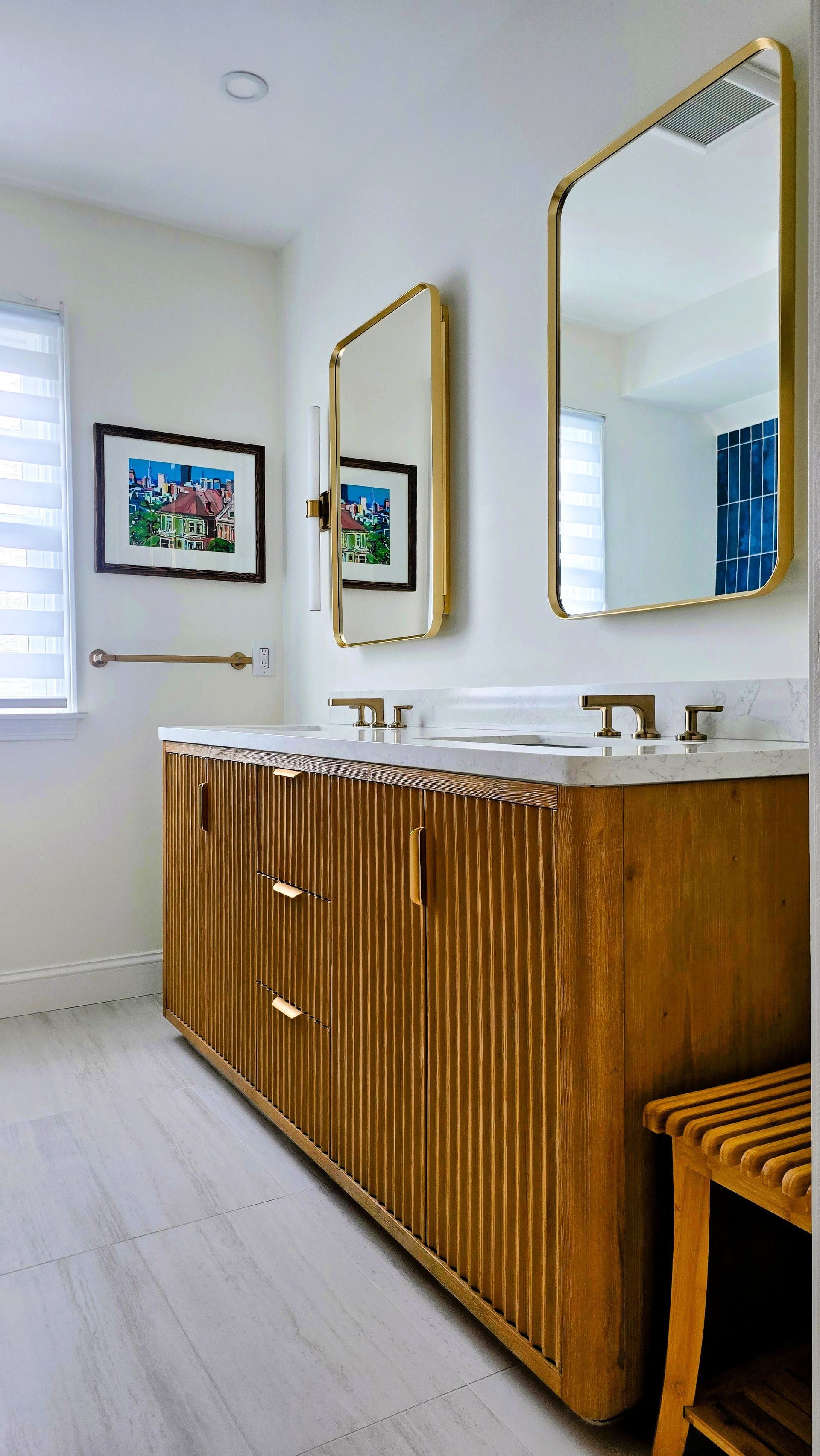 A bathroom vanity in Cromwell, CT with fluted wood cabinets, gold fixtures, two rectangular mirrors, and a white countertop.