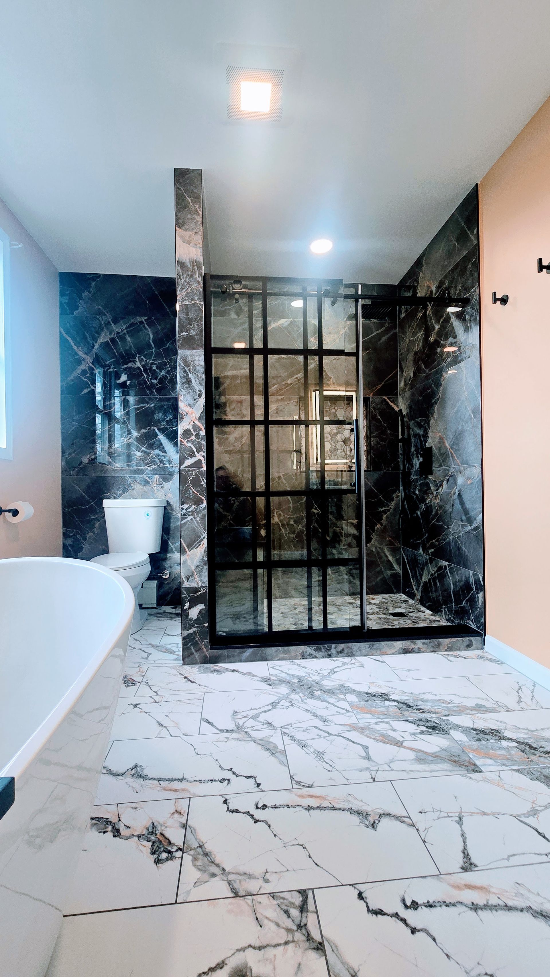 Bathroom Remodel in Seymour, CT completed by First Choice Bathroom Remodeling with Modern bathroom with marble floors and dark shower.