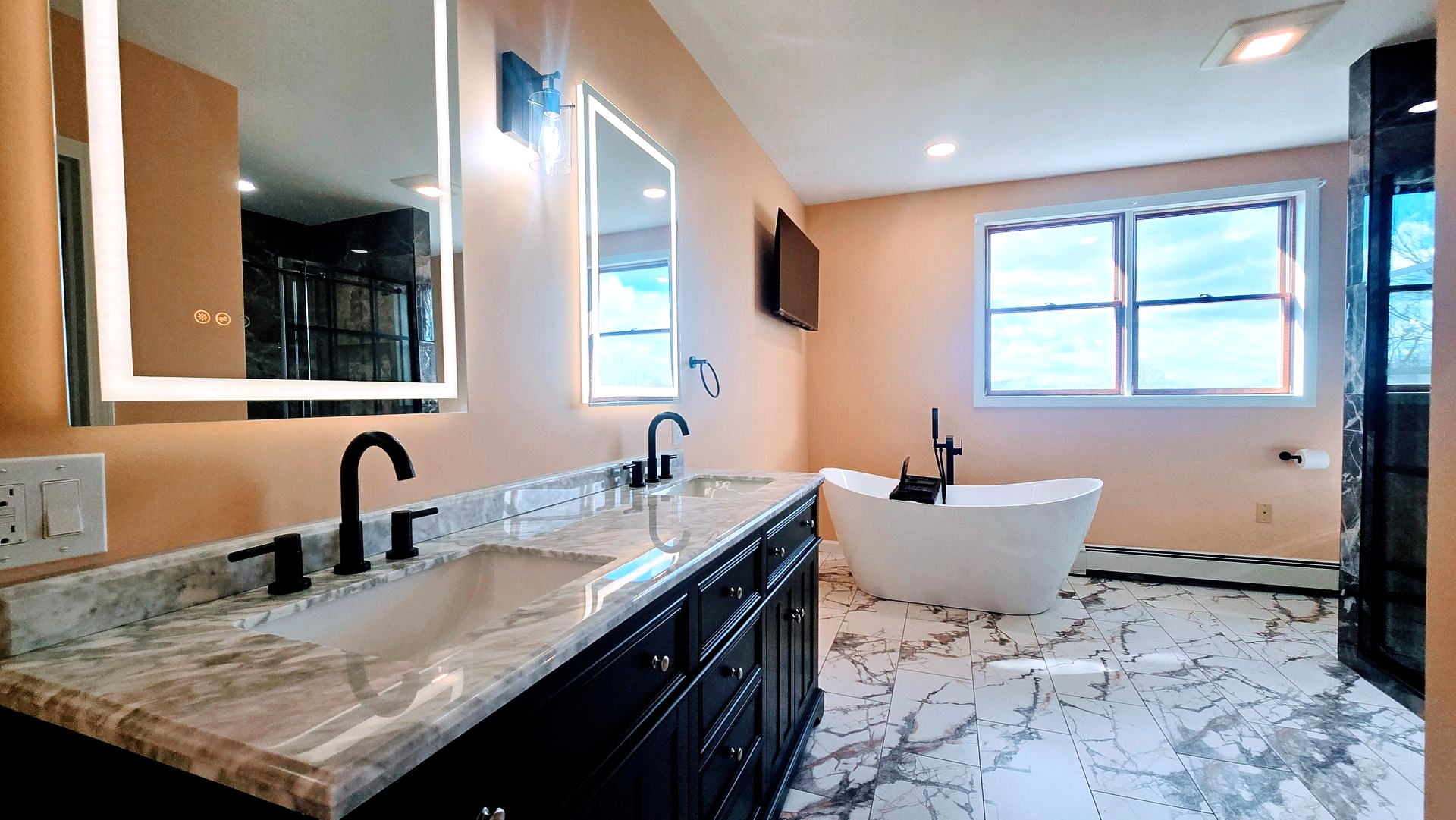Bathroom with a black vanity, marble countertop, soaking tub, and large windows.