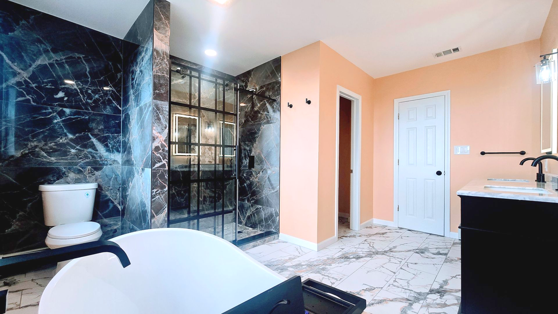Bathroom Remodel in Seymour, CT completed by First Choice Bathroom Remodeling. Modern bathroom with black marble shower, peach walls, black vanity, and white freestanding tub.