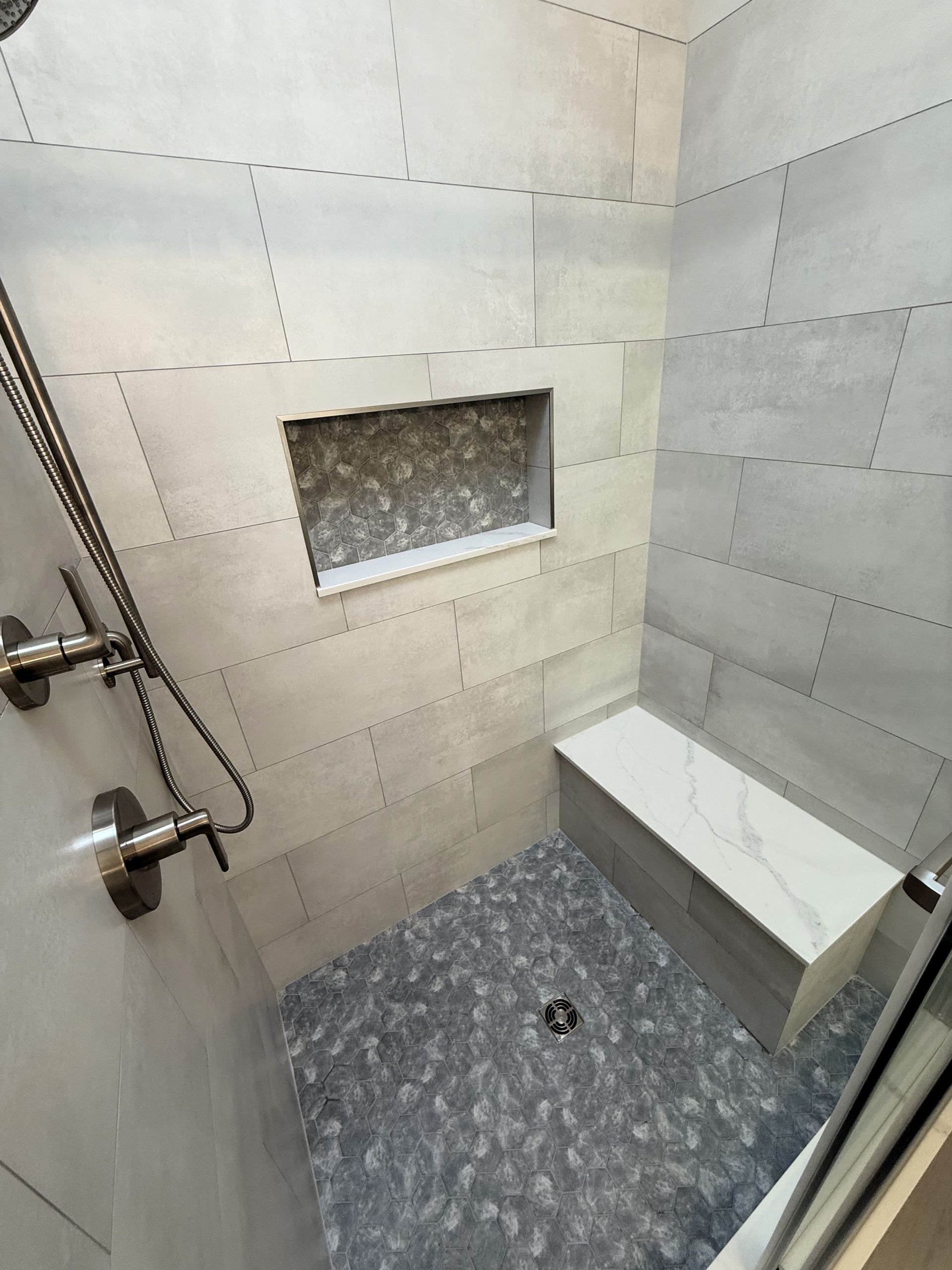A shower with a bench and a shower head