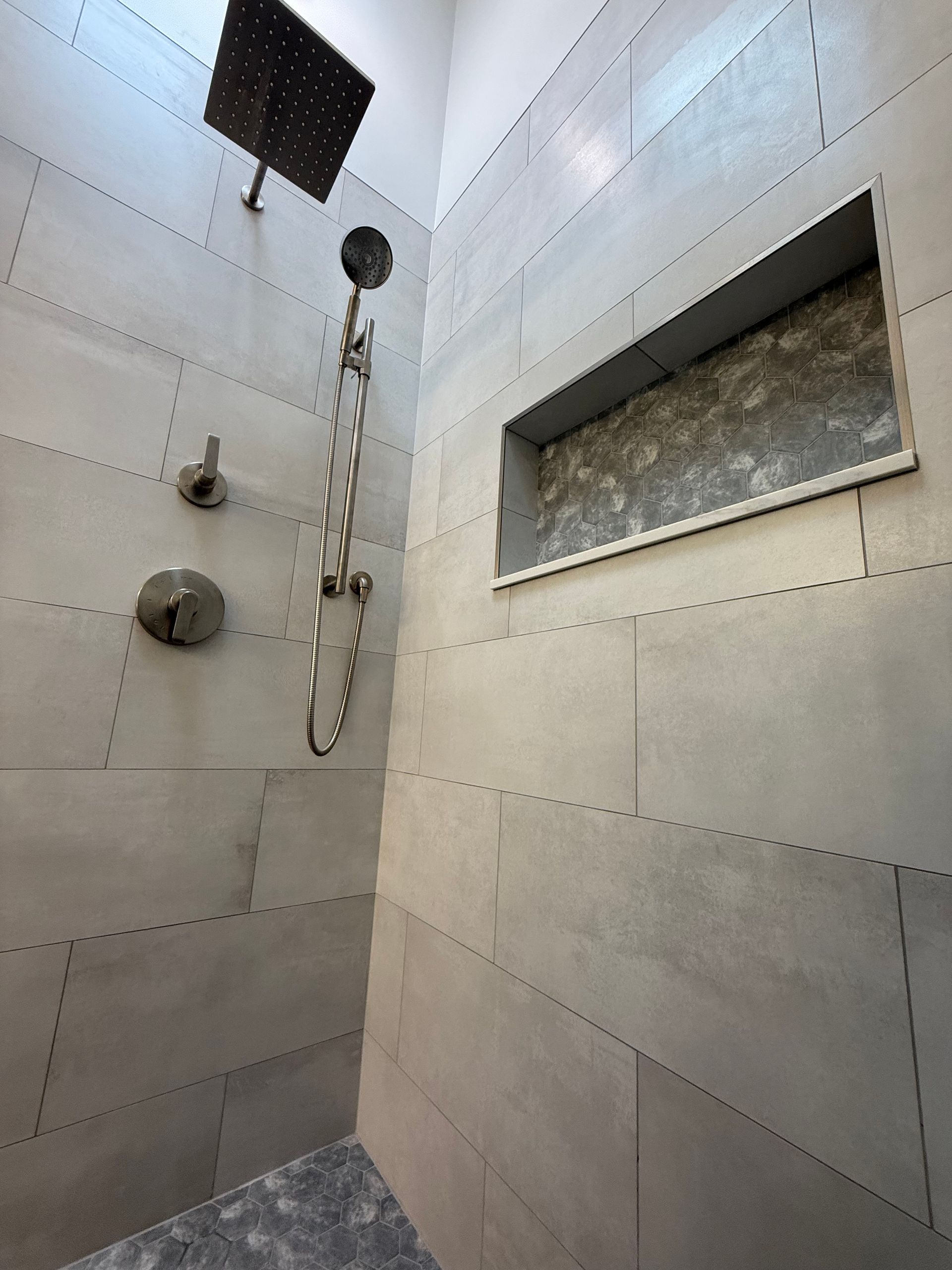 A shower with a built in shelf and a shower head