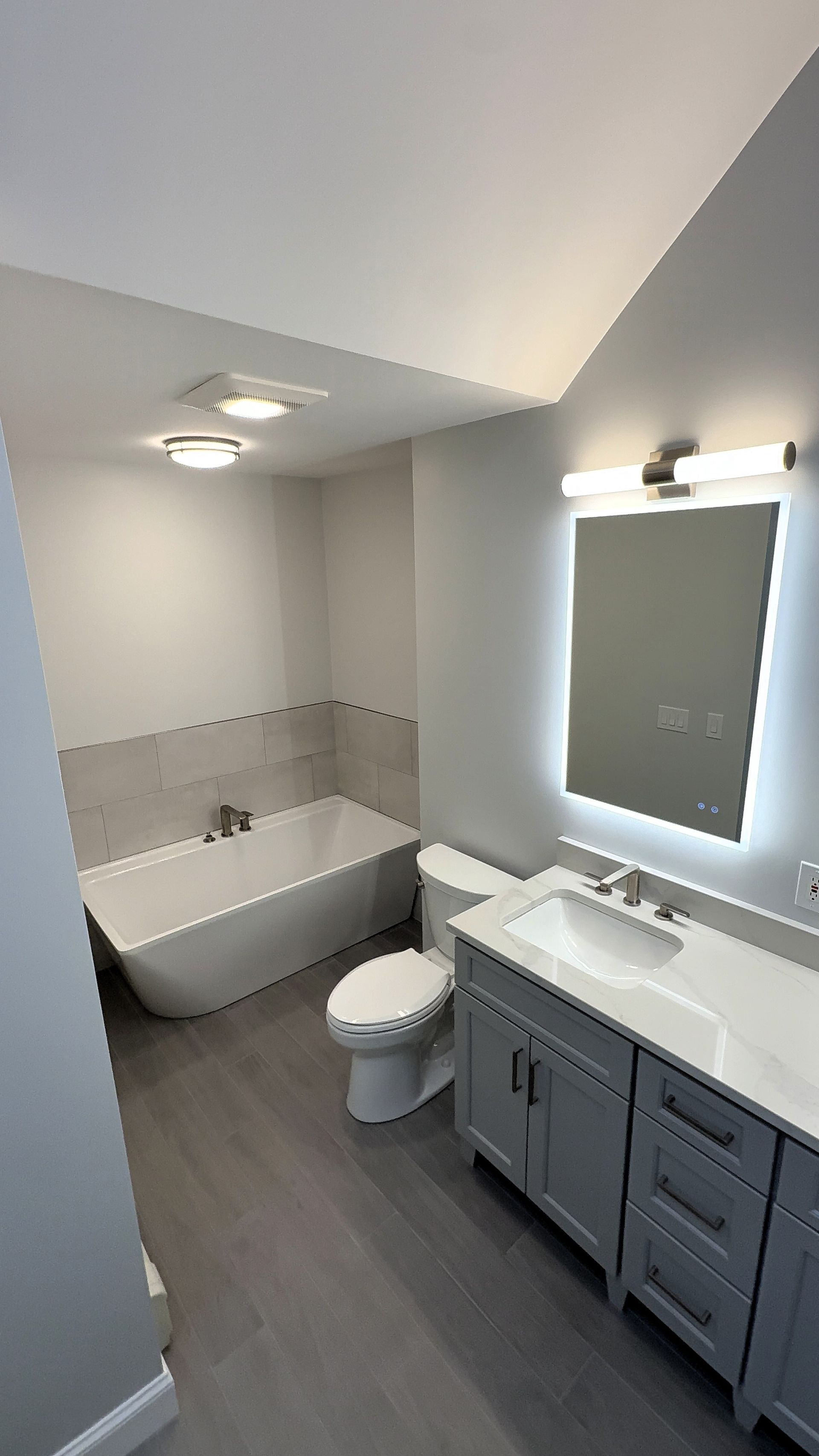 A bathroom with a tub , toilet , sink and mirror.