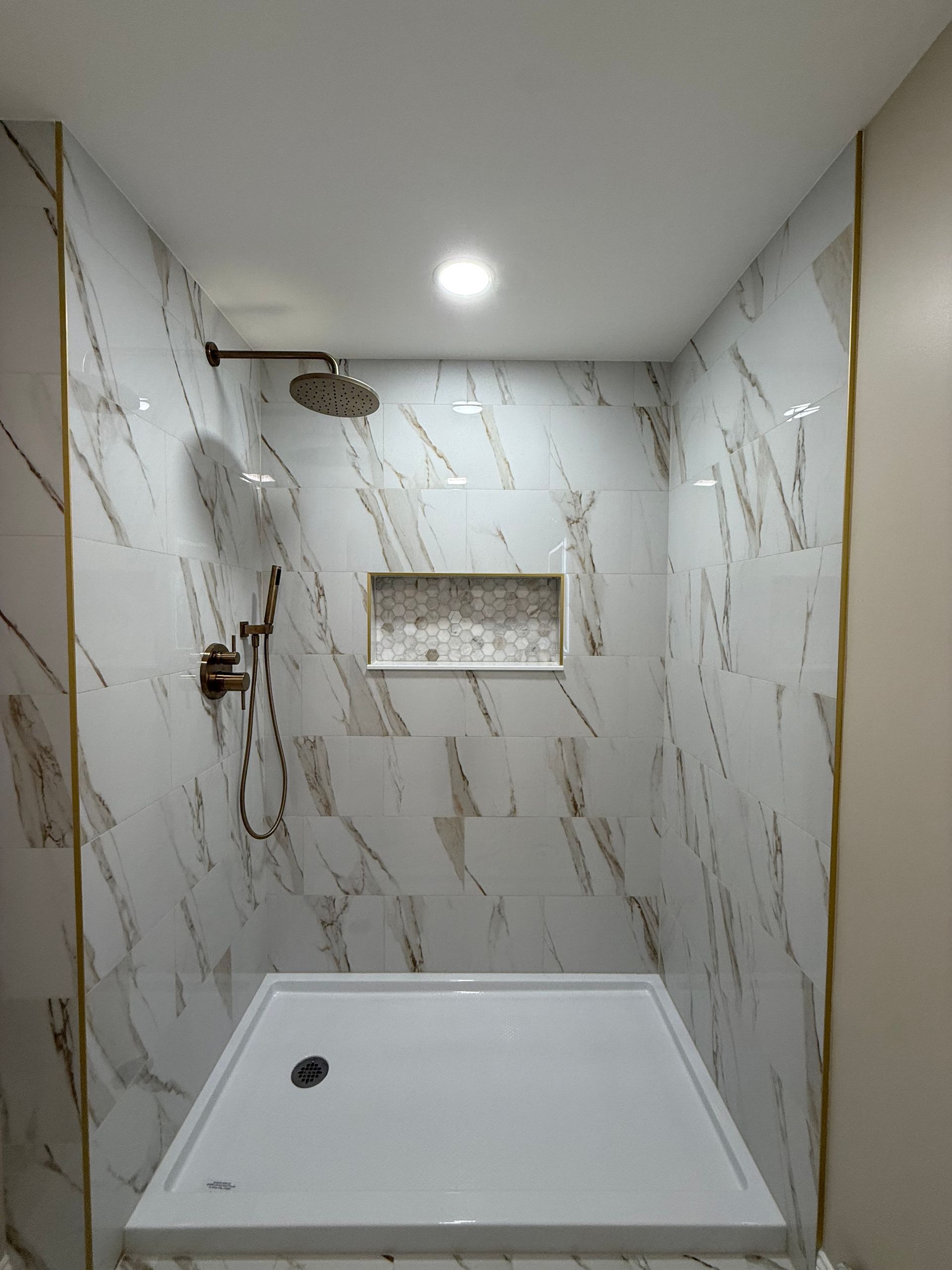 A shower with a sliding glass door and a shower head.
