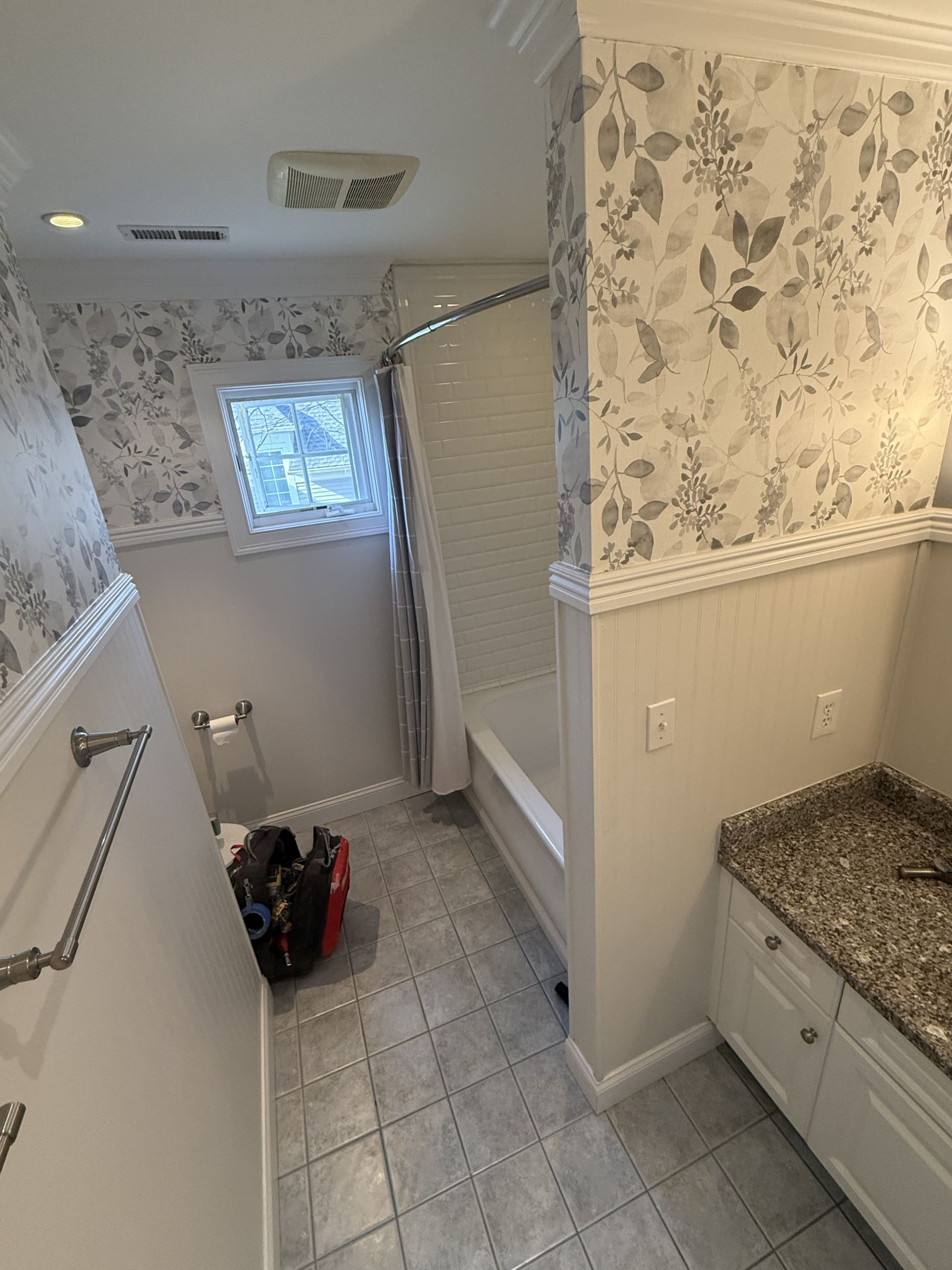 A bathroom with a bathtub , sink , and window.
