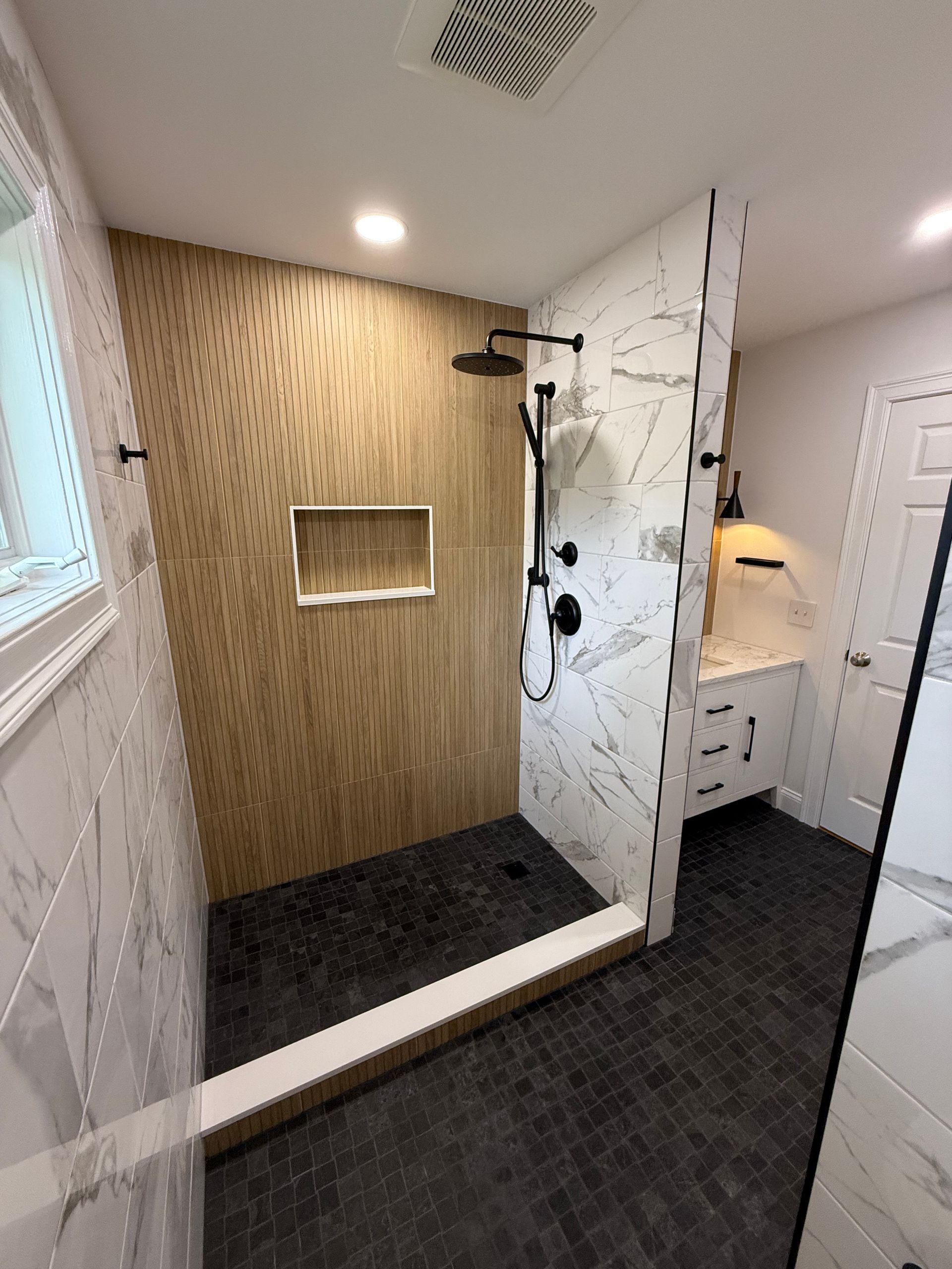 A shower with a sliding glass door and a shower head.