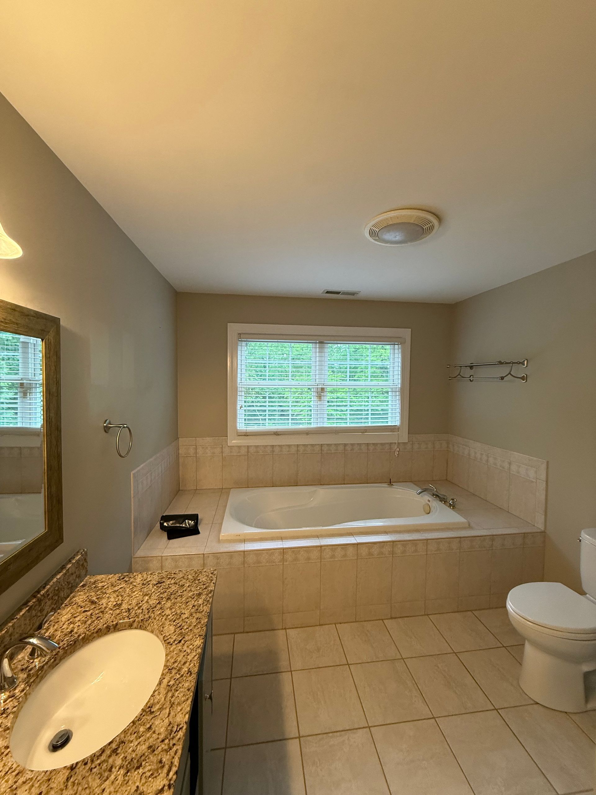 A bathroom with a tub , sink , mirror and window.