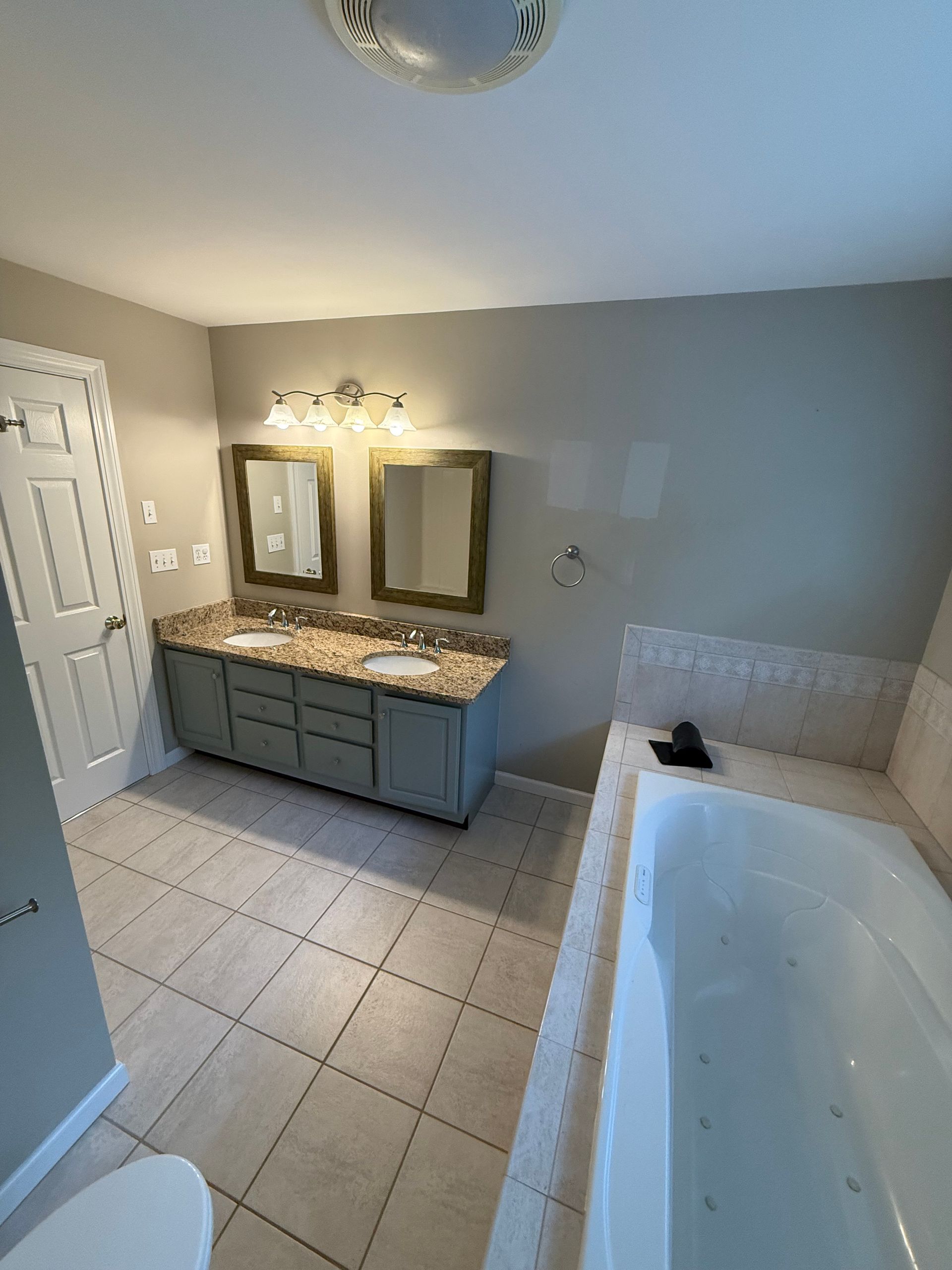 A bathroom with two sinks , two mirrors , a tub and a toilet.