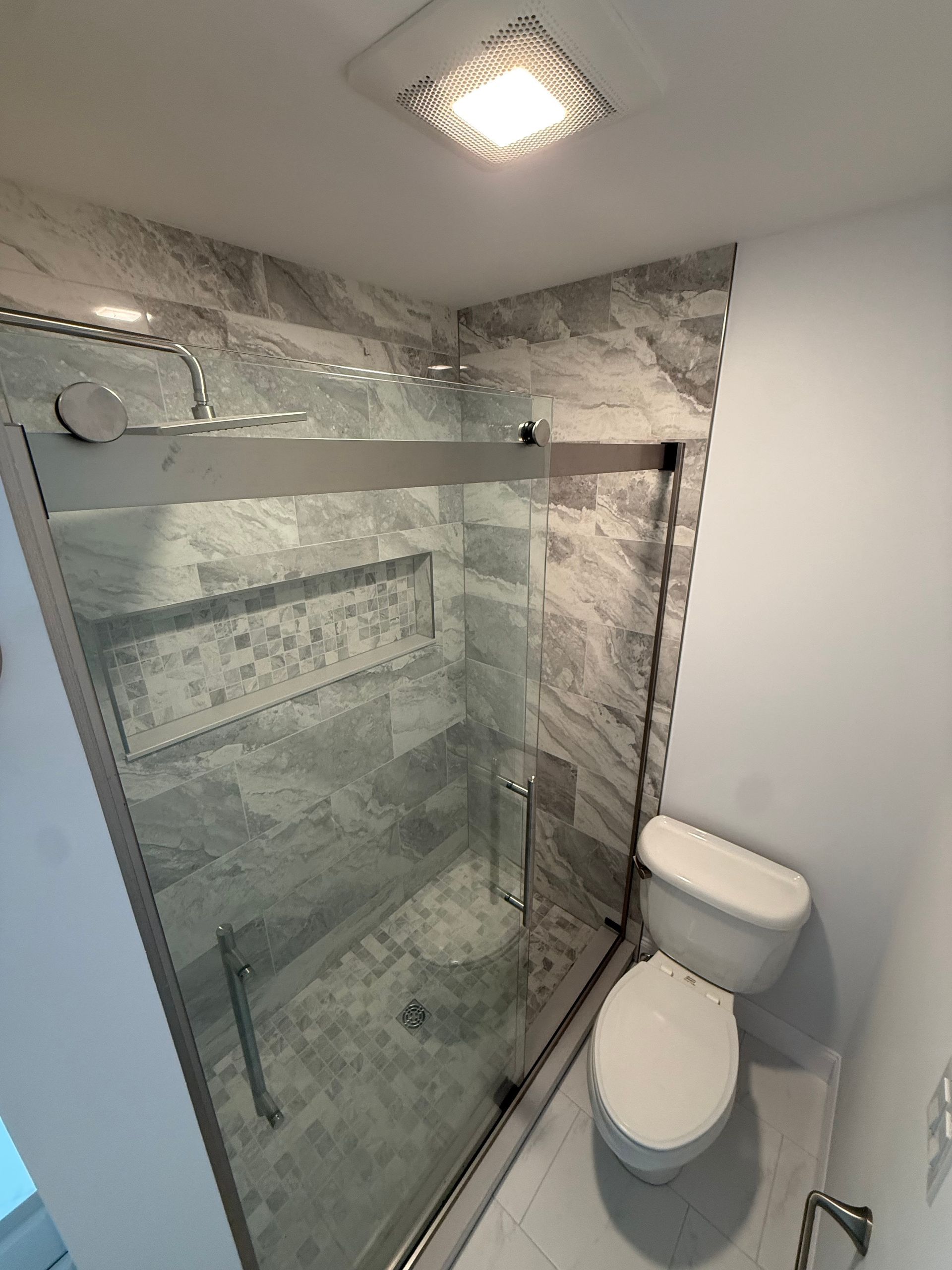 A shower with a built in shelf and a shower head