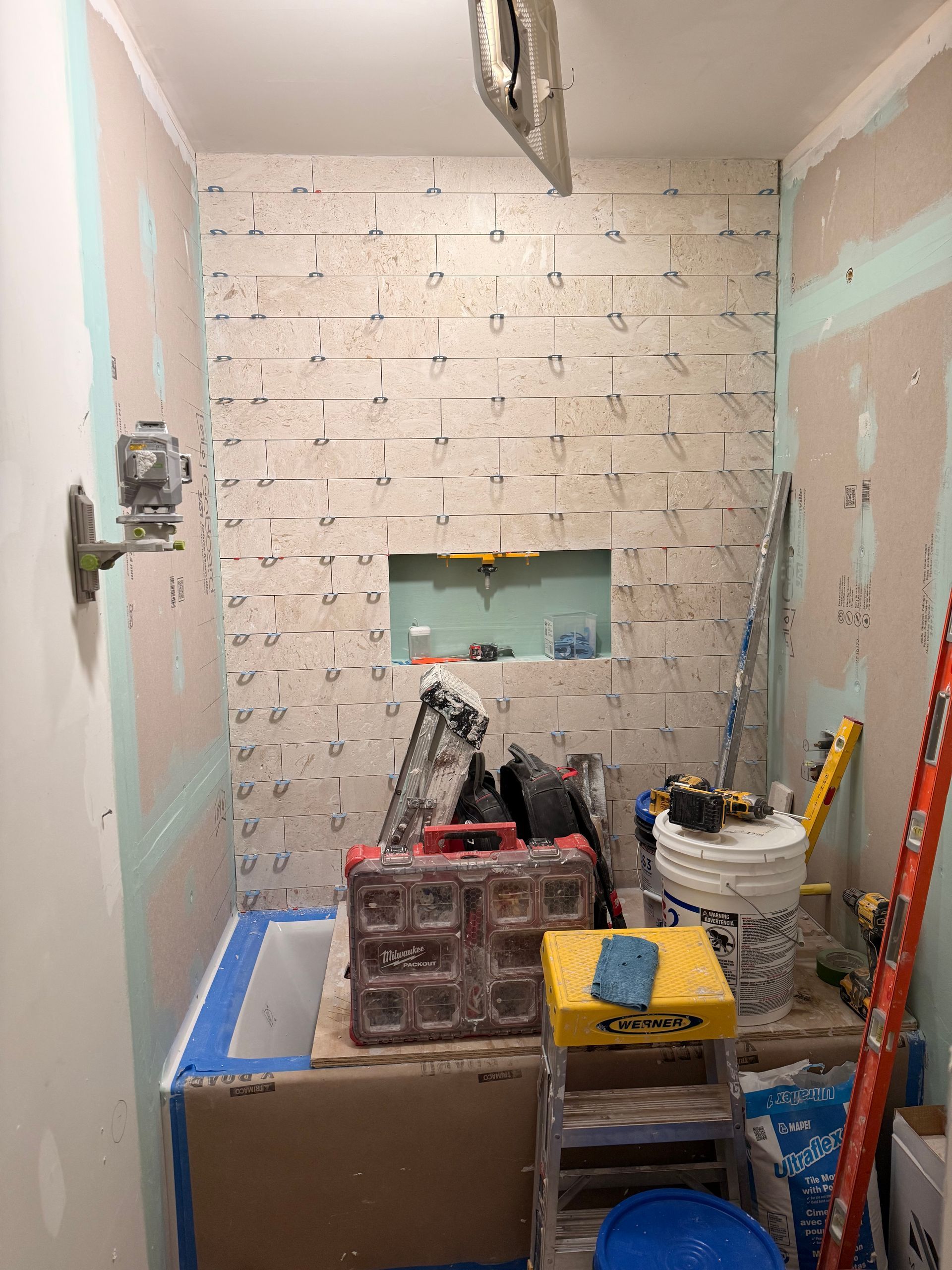 Bathroom remodel in progress: with tiled accent wall and tools.