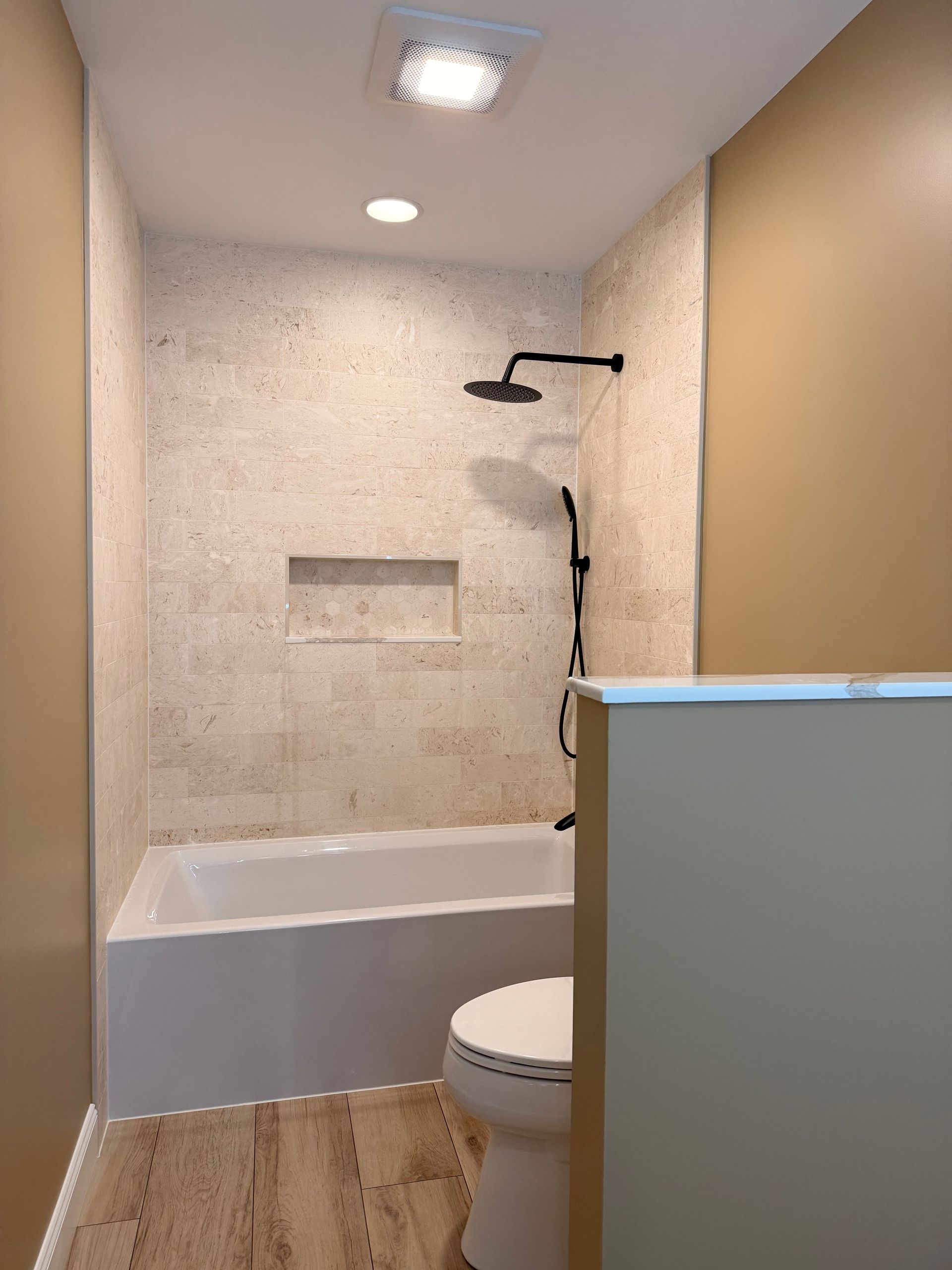 Bronze floor-mounted faucet with handheld shower head; lever and knob controls.