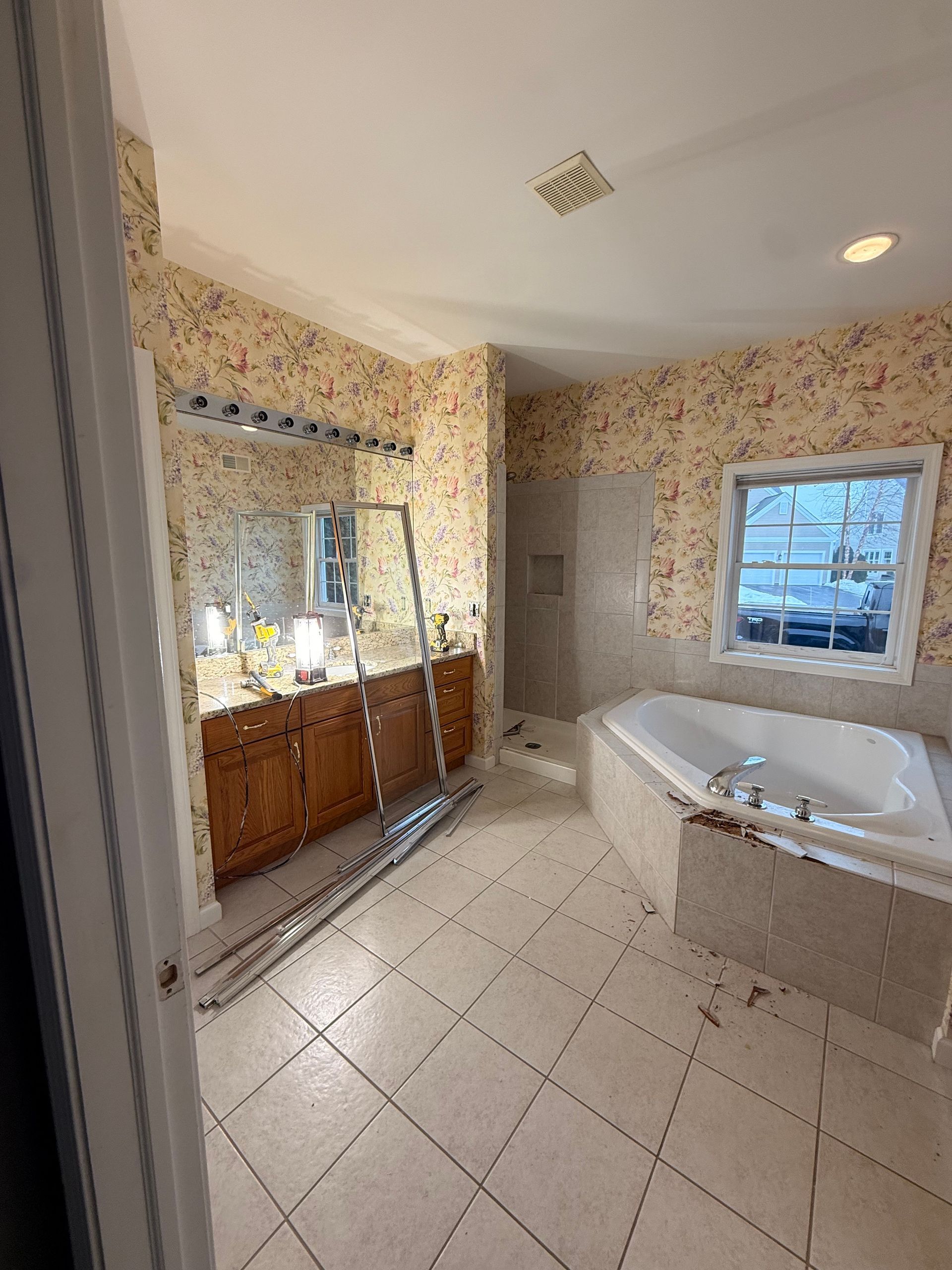 Exposed wall studs with plumbing pipes and a shower valve installed in a room under construction.