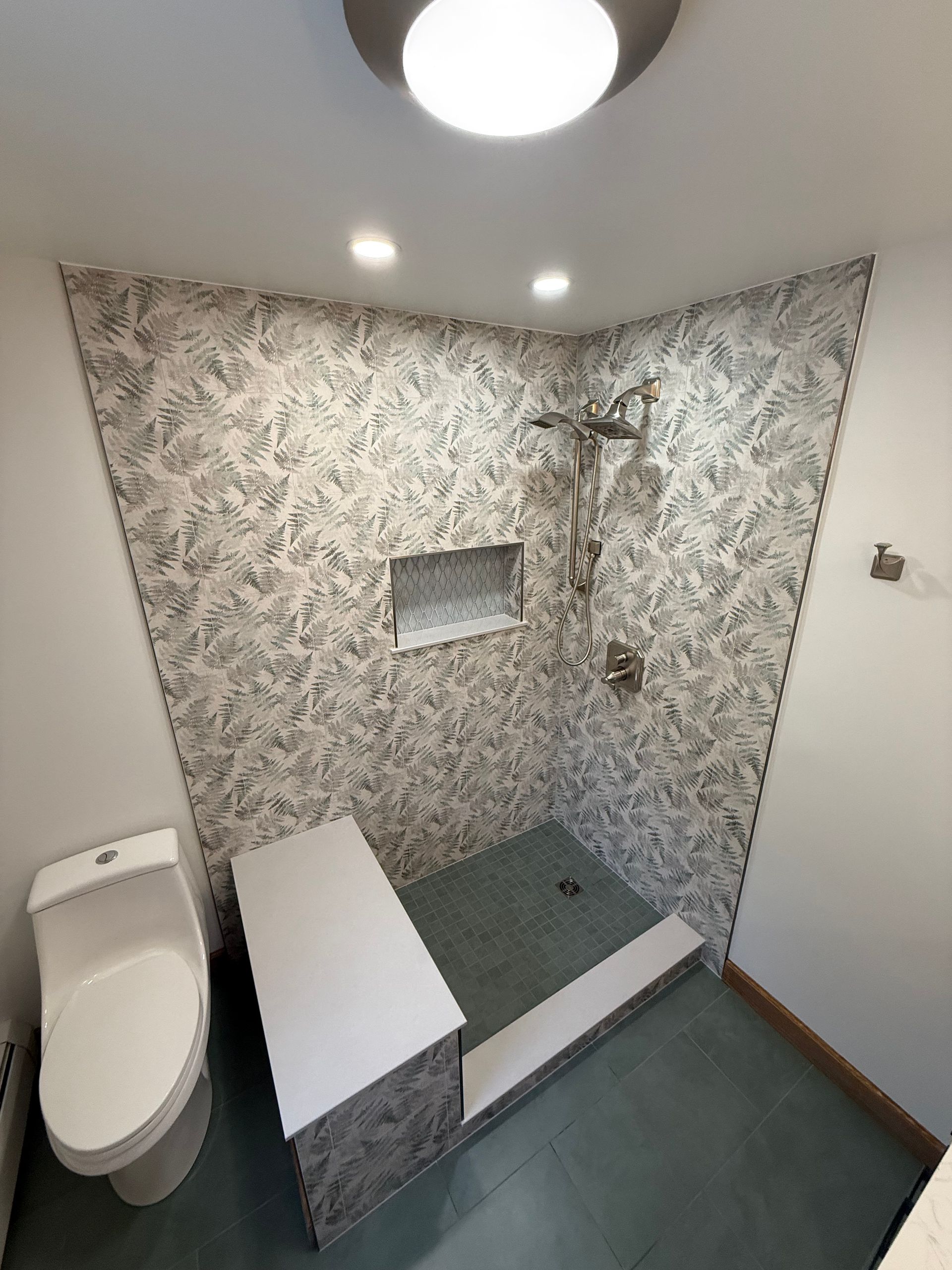 A bathroom with a walk in shower mosaic tiles on the shower floor.