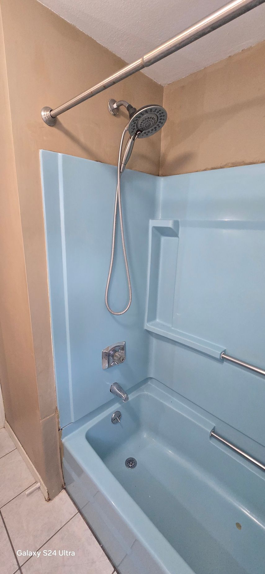 A bathroom with a shower , sink , and door.