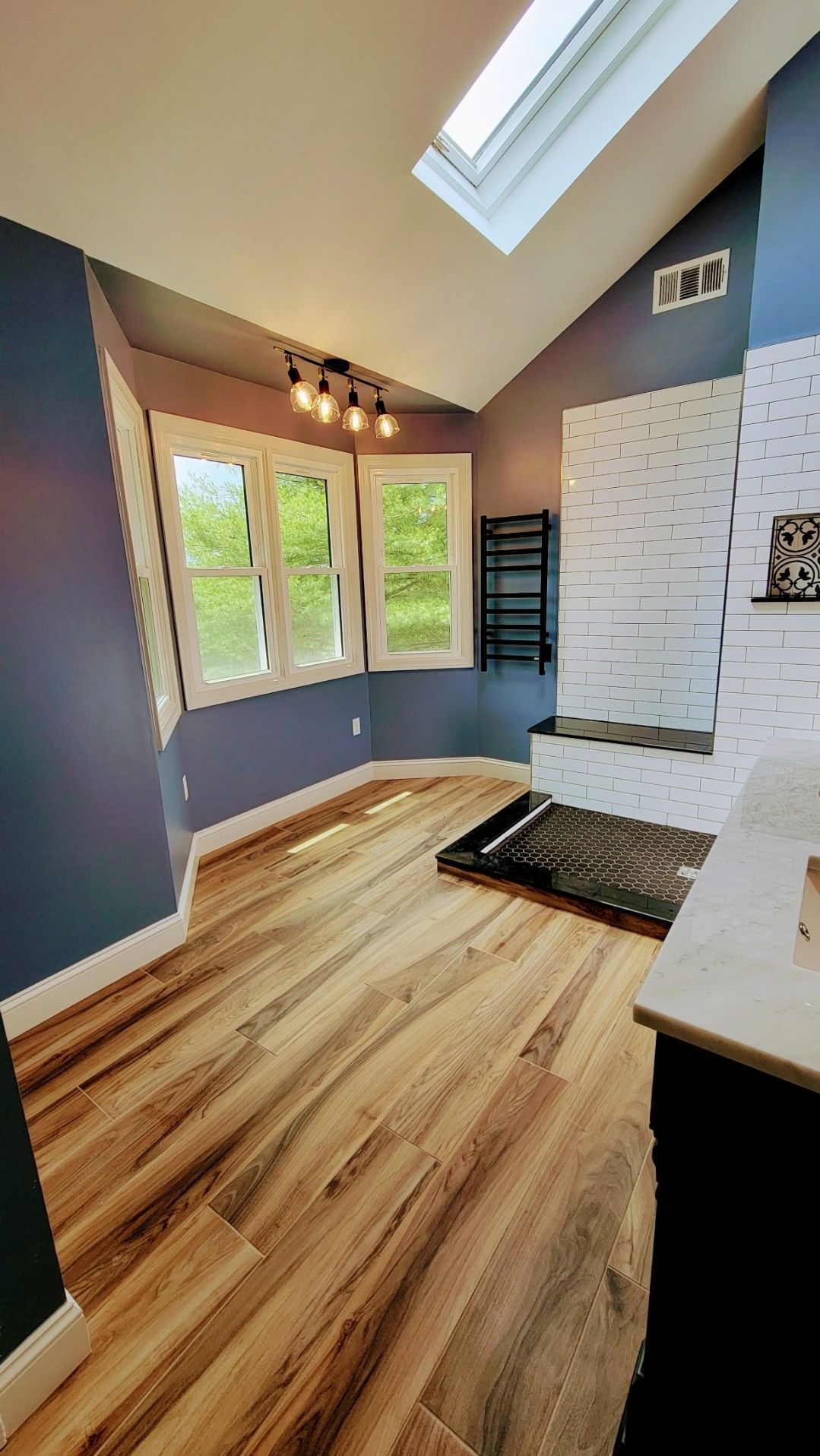 A bathroom with hardwood floors and a skylight.