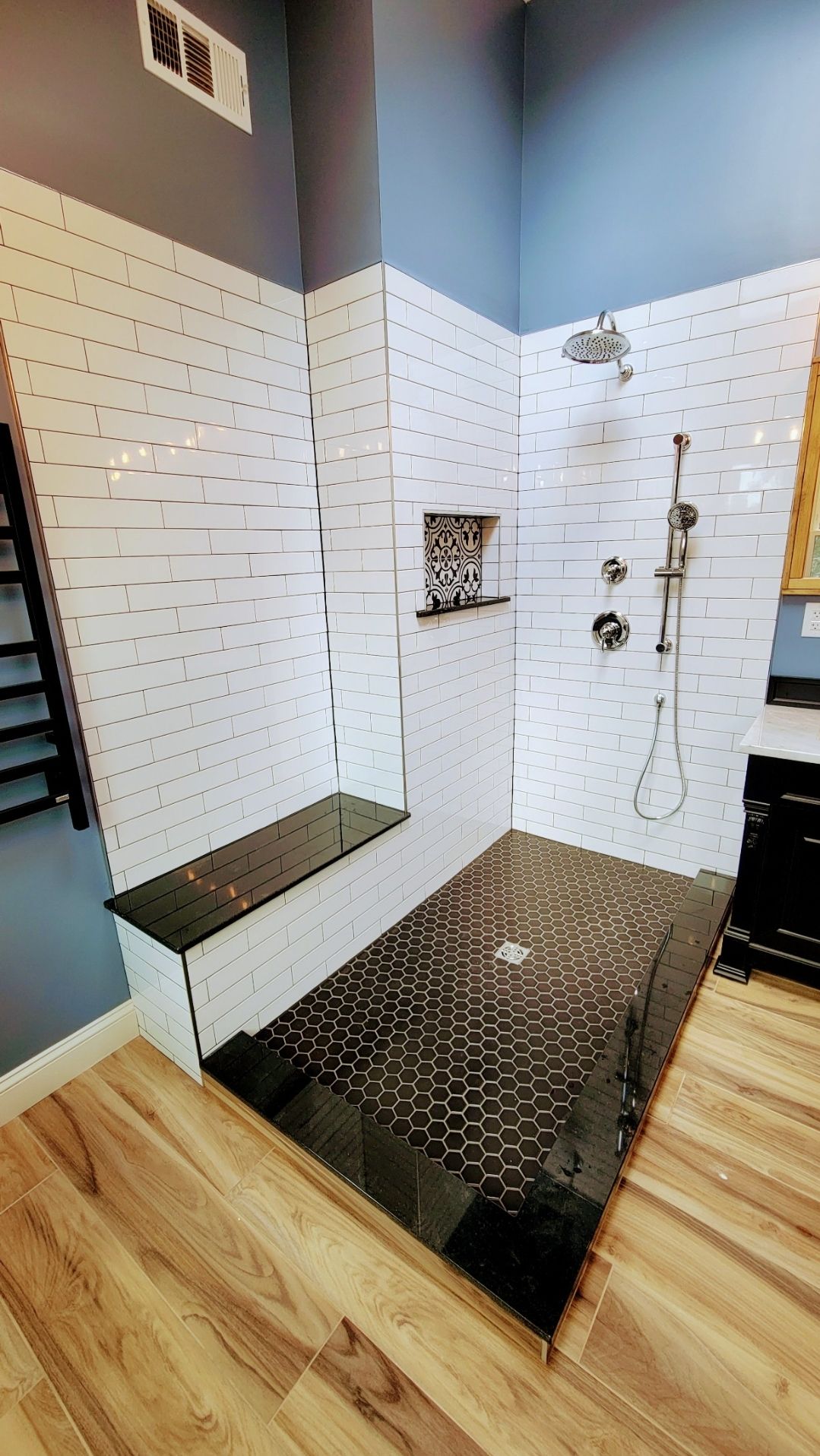 A bathroom with a walk in shower and a bench.