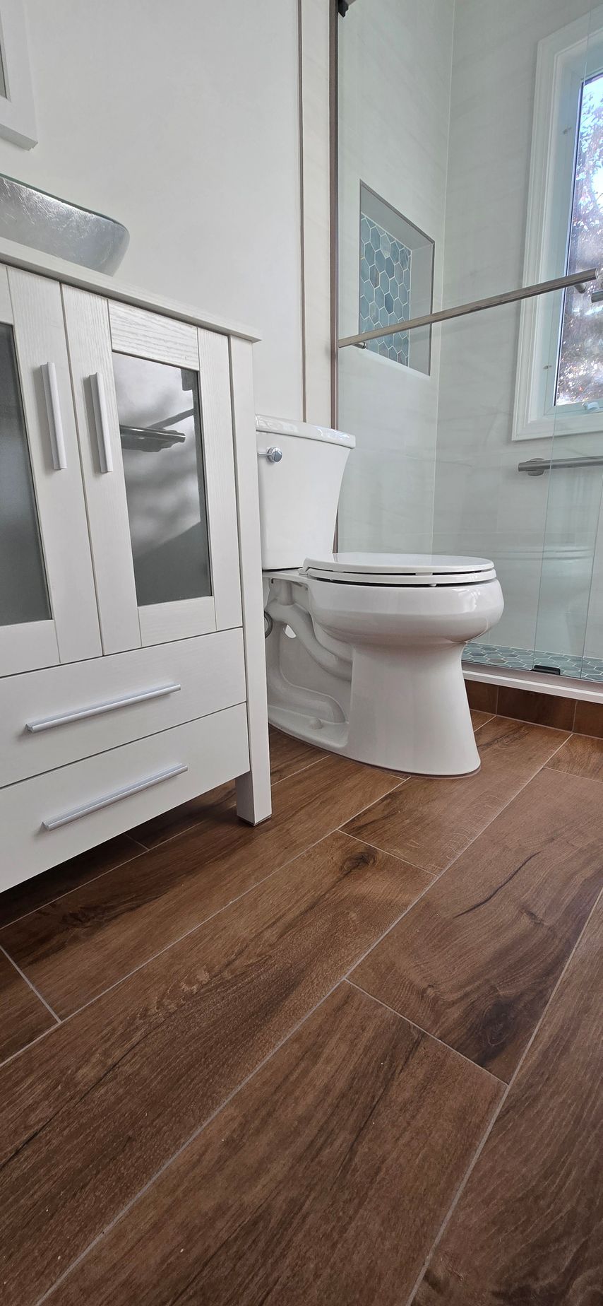 A bathroom with a walk in shower with a wooden wall and marble tiles.