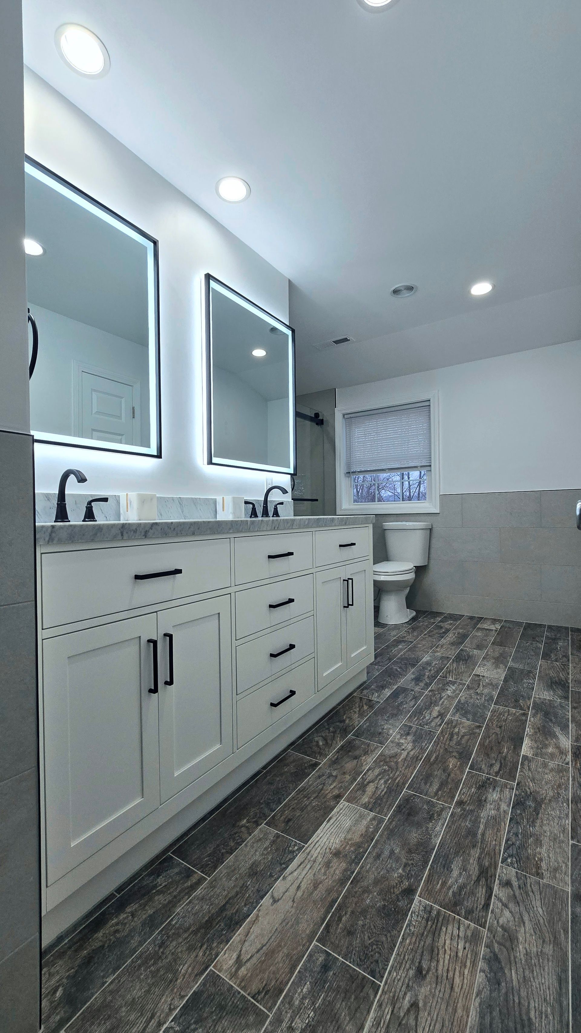 Luxurious bathroom with dark green vanity, glass shower enclosure, and a patterned rug.