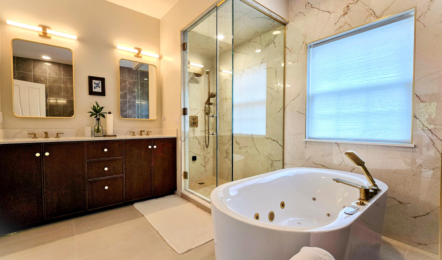 Modern bathroom in Cromwell, CT 
with double vanity, glass shower, and white soaking tub near a window.