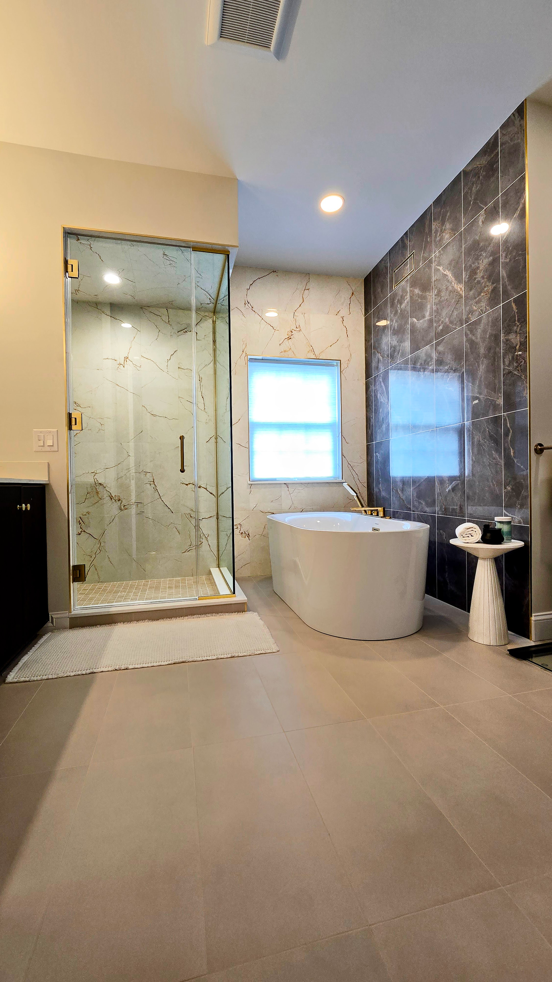 Modern bathroom  in Cromwell, CT on the TPC River Highlands Golf Course with glass shower, freestanding tub, and dark marble accent wall
