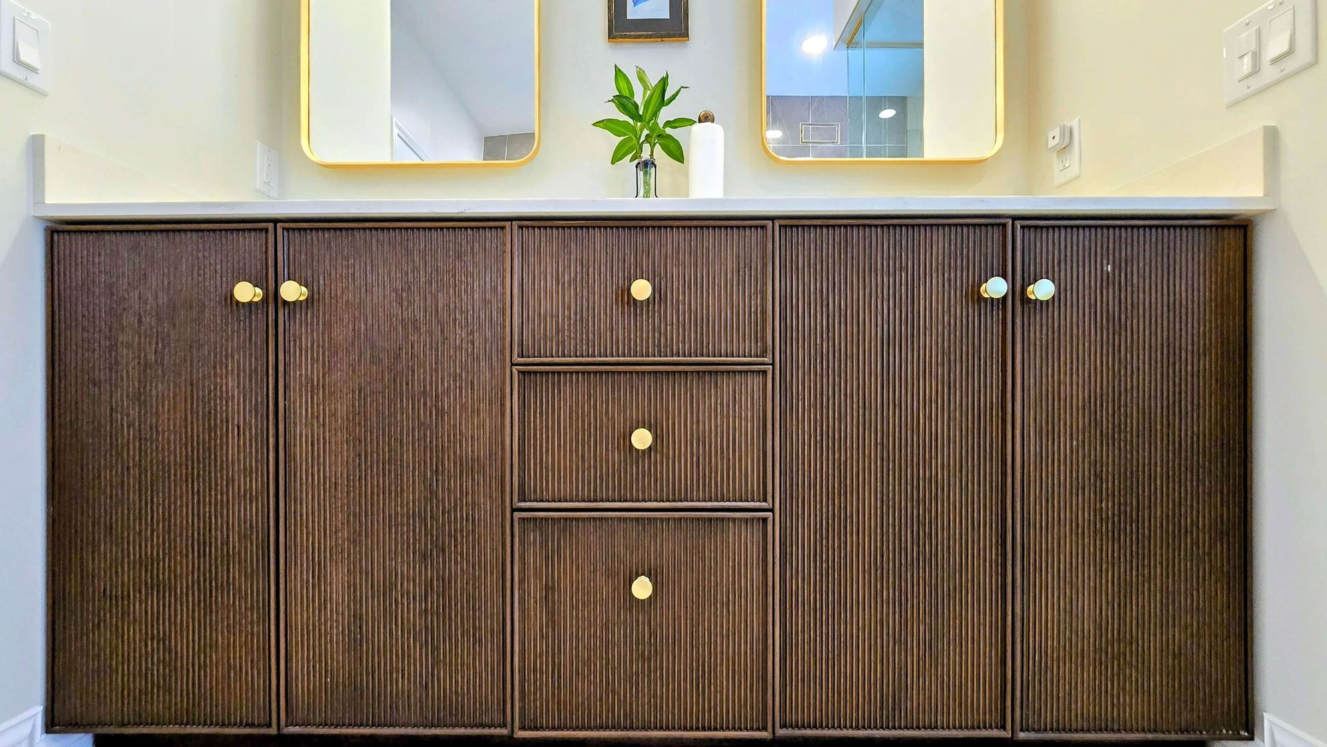 Dark wood bathroom vanity with drawers and cabinets beneath a countertop sink.