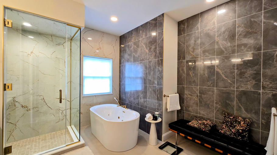 Modern bathroom in Cromwell, CT with glass shower, freestanding tub, and dark tiled wall with fireplace