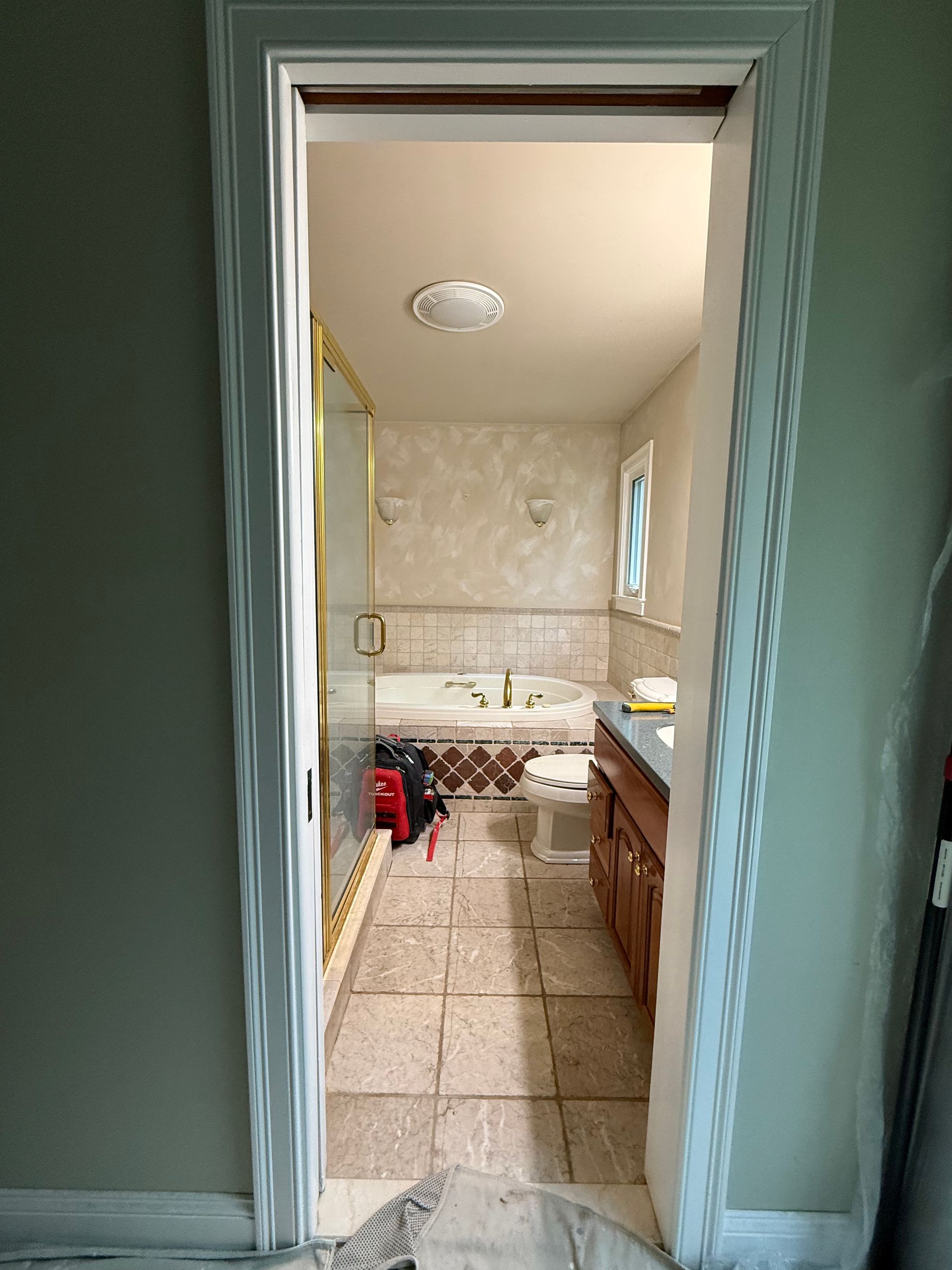 View through a doorway into a bathroom with a tub, toilet, and vanity.