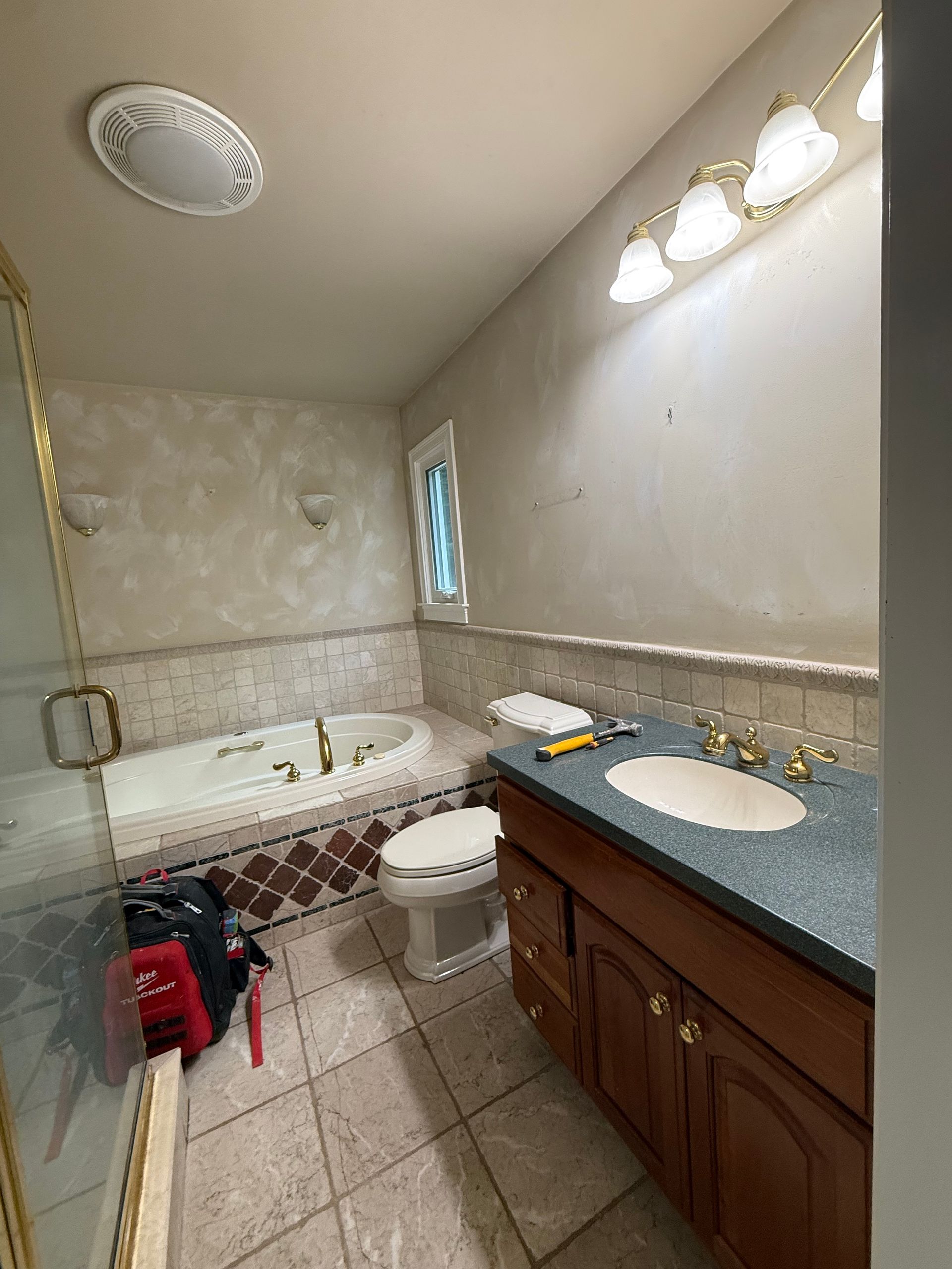 Bathroom with a jacuzzi, toilet, vanity, and tan-tiled floor.