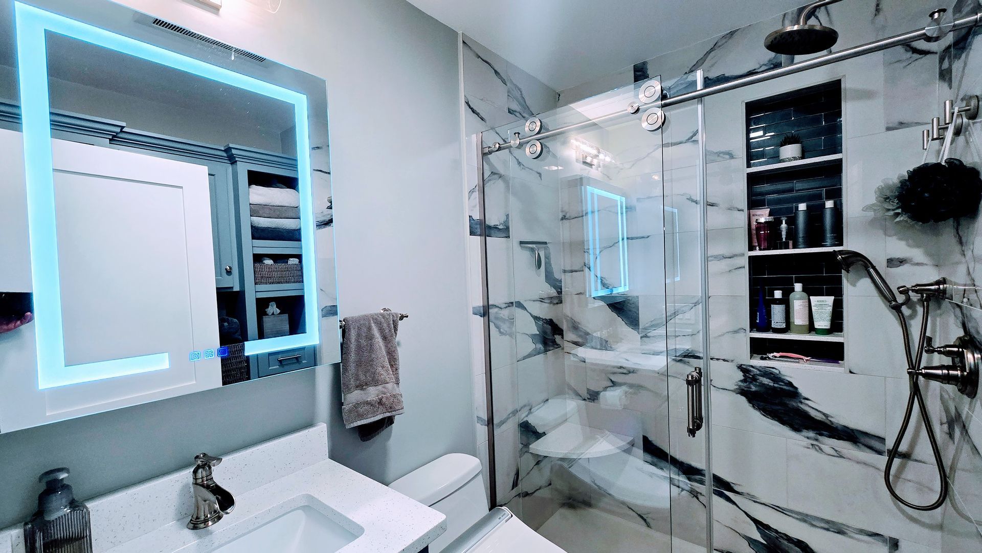Modern West Hartford bathroom with marble shower, LED-lit mirror, and white countertop.