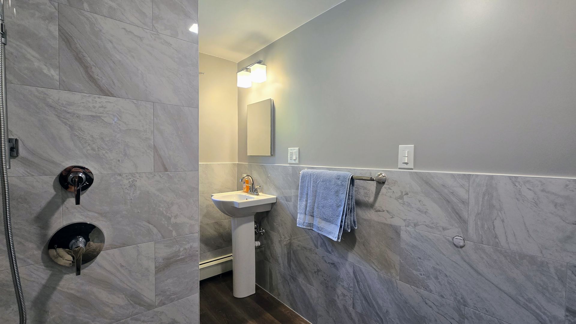 Southington bathroom with grey tile walls and shower, pedestal sink, towel rack.