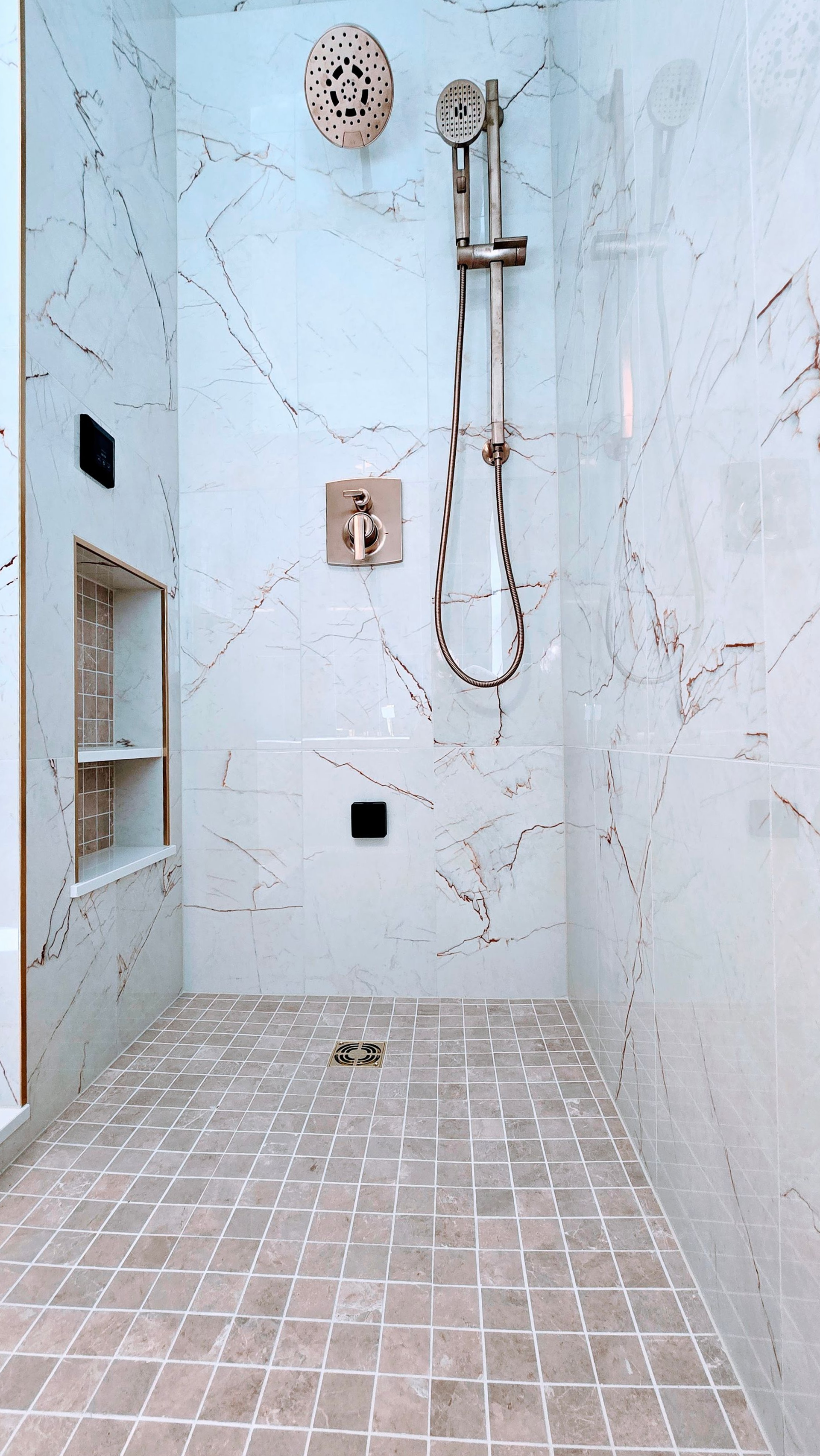 Modern walk-in steam shower  in Cromwell, CT on the TPC River Highlands Golf Course with shower area with white tiled walls and floor, mounted showerhead, hose, and drain grate.