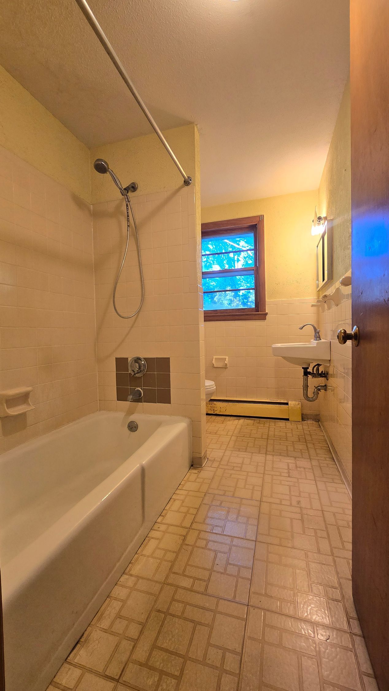 Southington bathroom with bathtub, sink, and window. Beige tile and yellow walls.