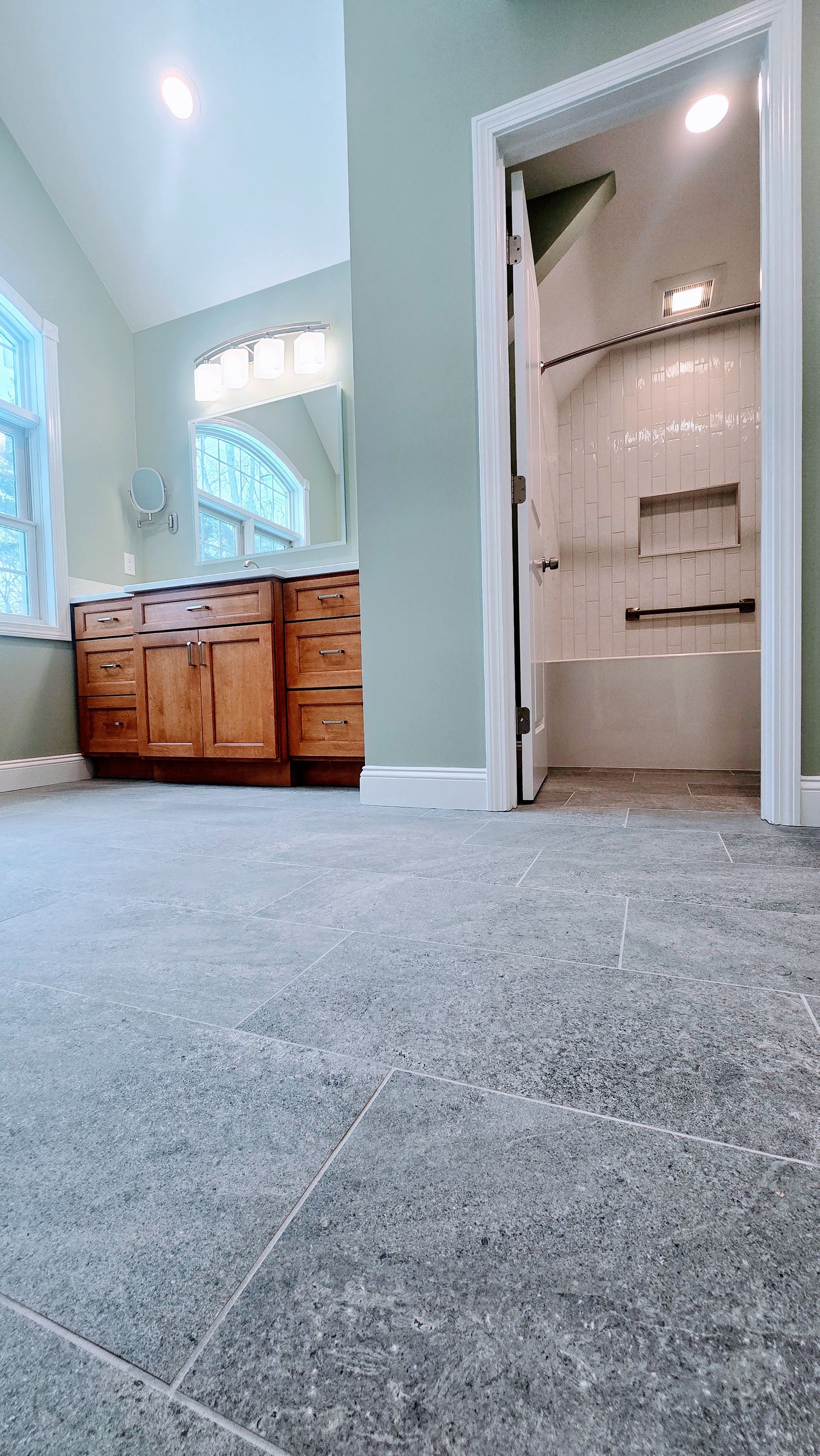 A bathroom remodel in Bristol, CT completed by First Choice Bathroom Remodeling with white tub, speckled shower tile, black shower fixtures, and a recessed shelf.