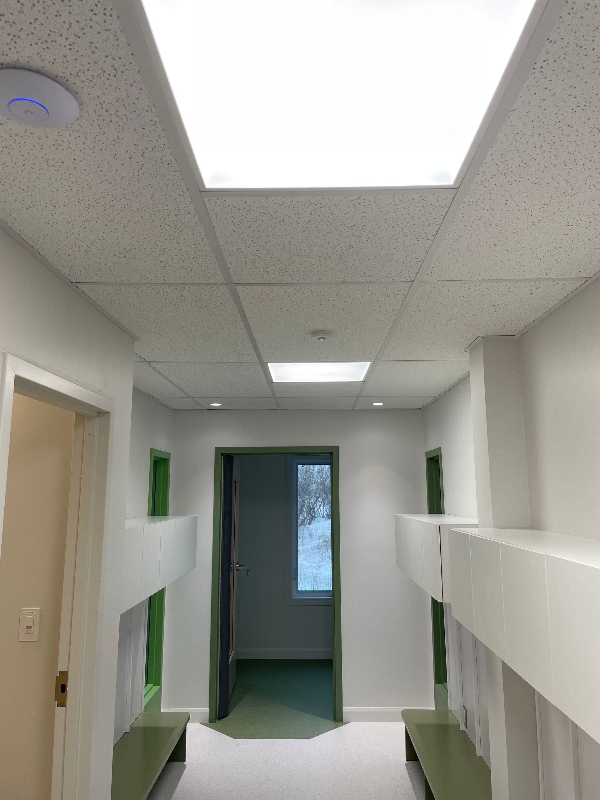 Un couloir avec une lumière au plafond et une fenêtre.