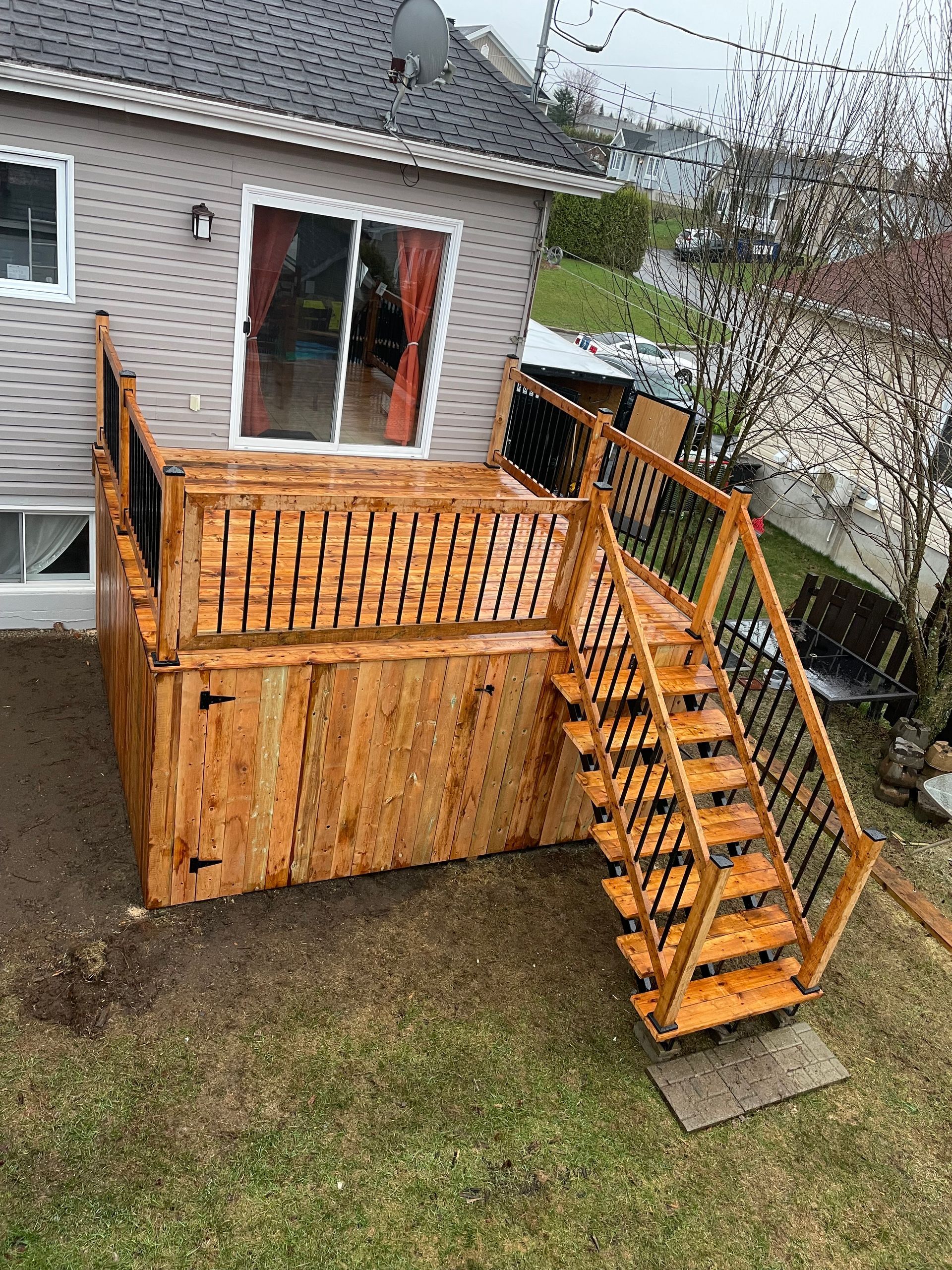 Une terrasse en bois avec des escaliers qui y mènent se trouve devant une maison.