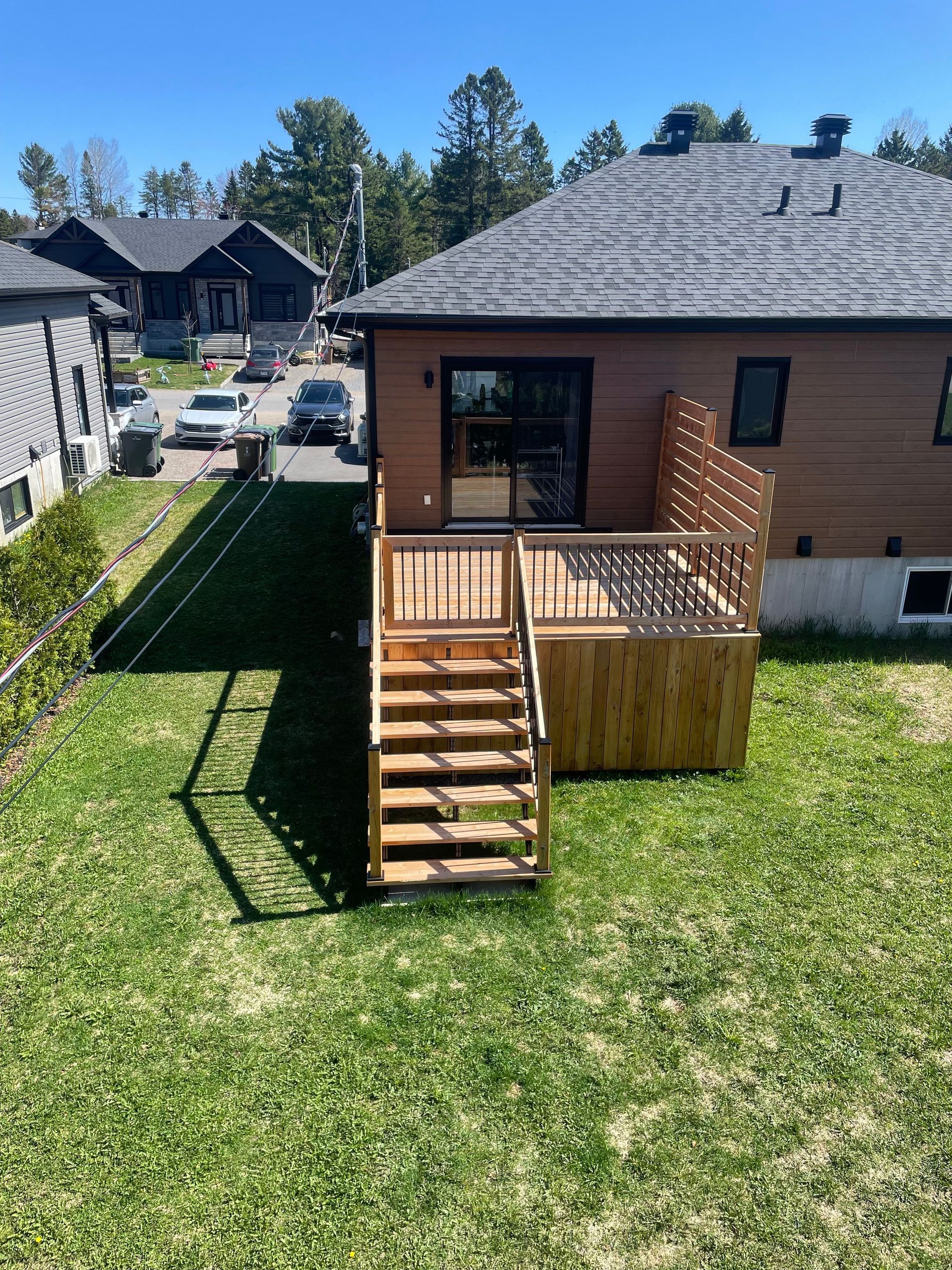 Une vue aérienne d'une maison avec une terrasse en bois et des escaliers dans l'arrière-cour.