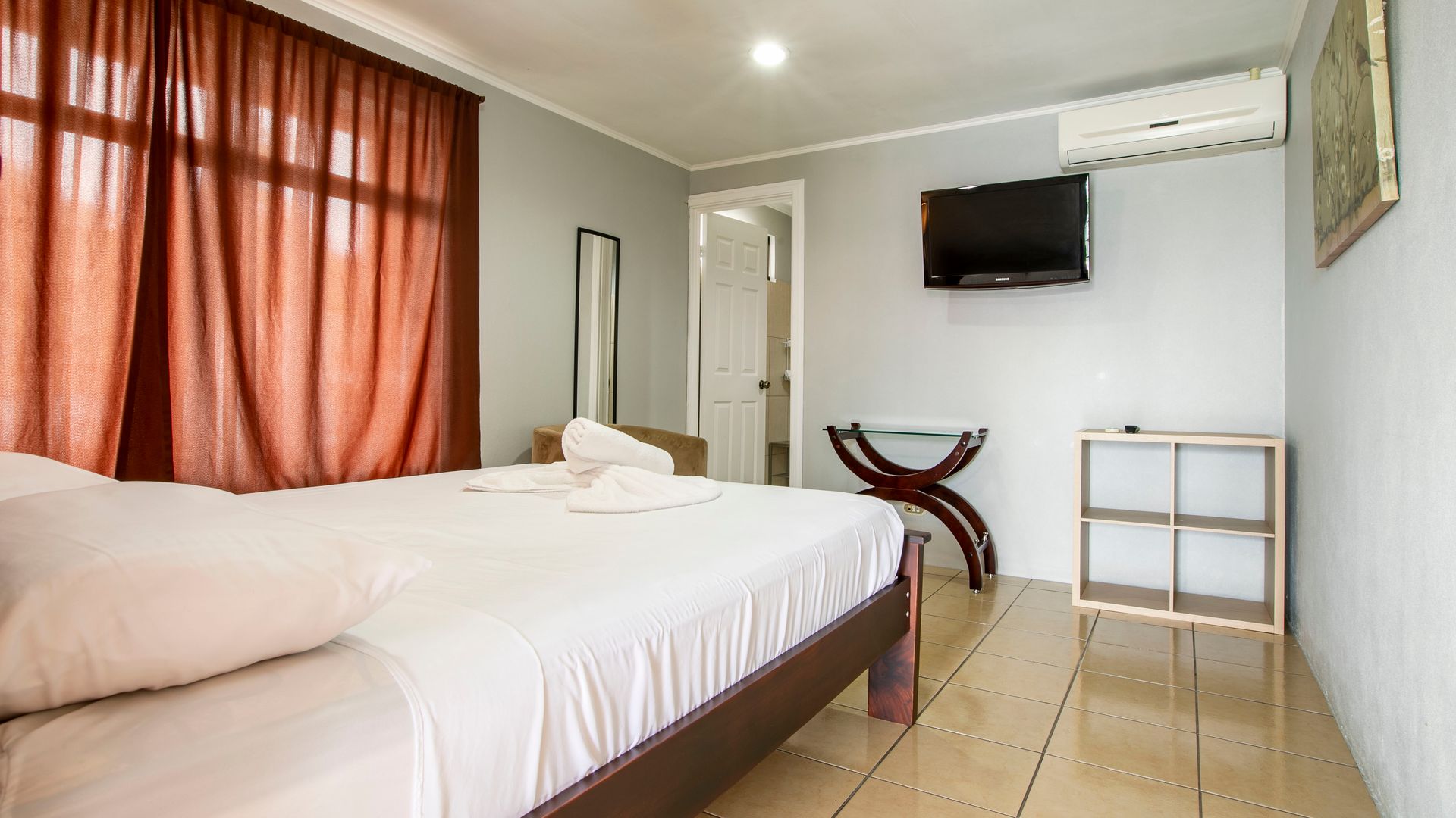 a hotel room with a bed , television and air conditioner .