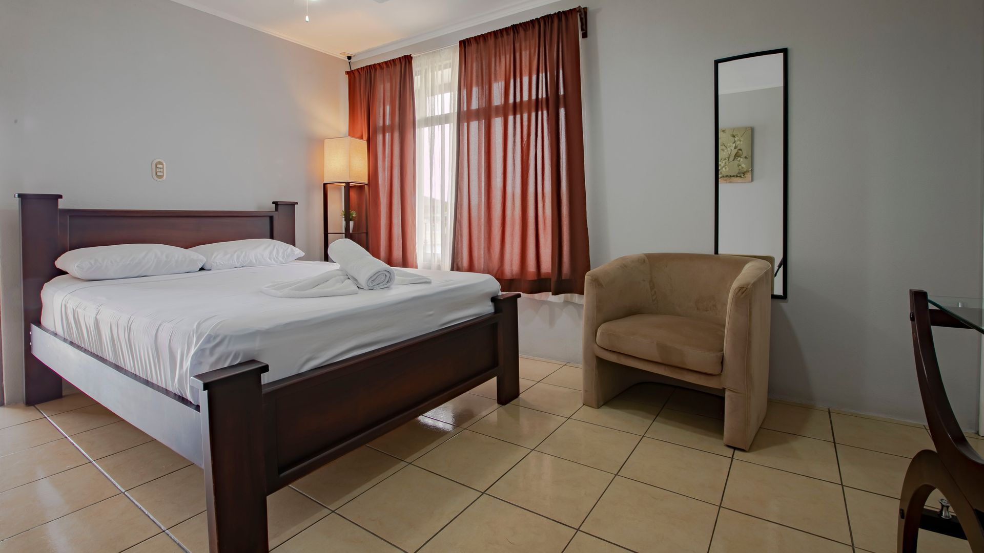 a bedroom with a bed , chair and mirror