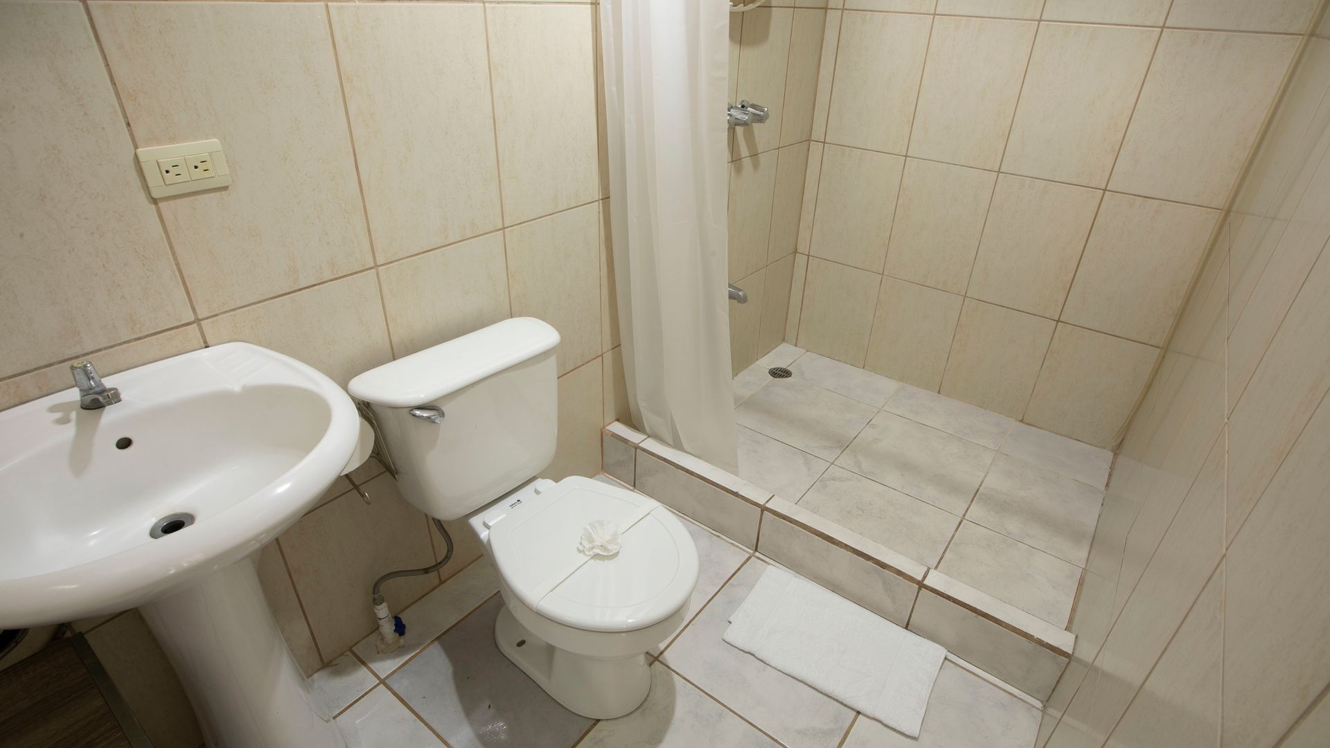 a bathroom with a toilet , sink and shower .